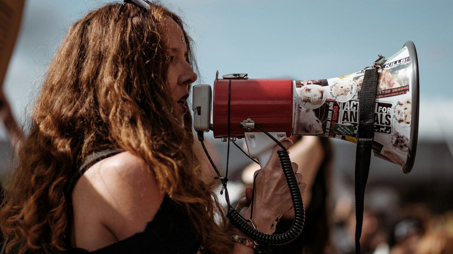 Mulher falando em um megafone, durante um protesto.