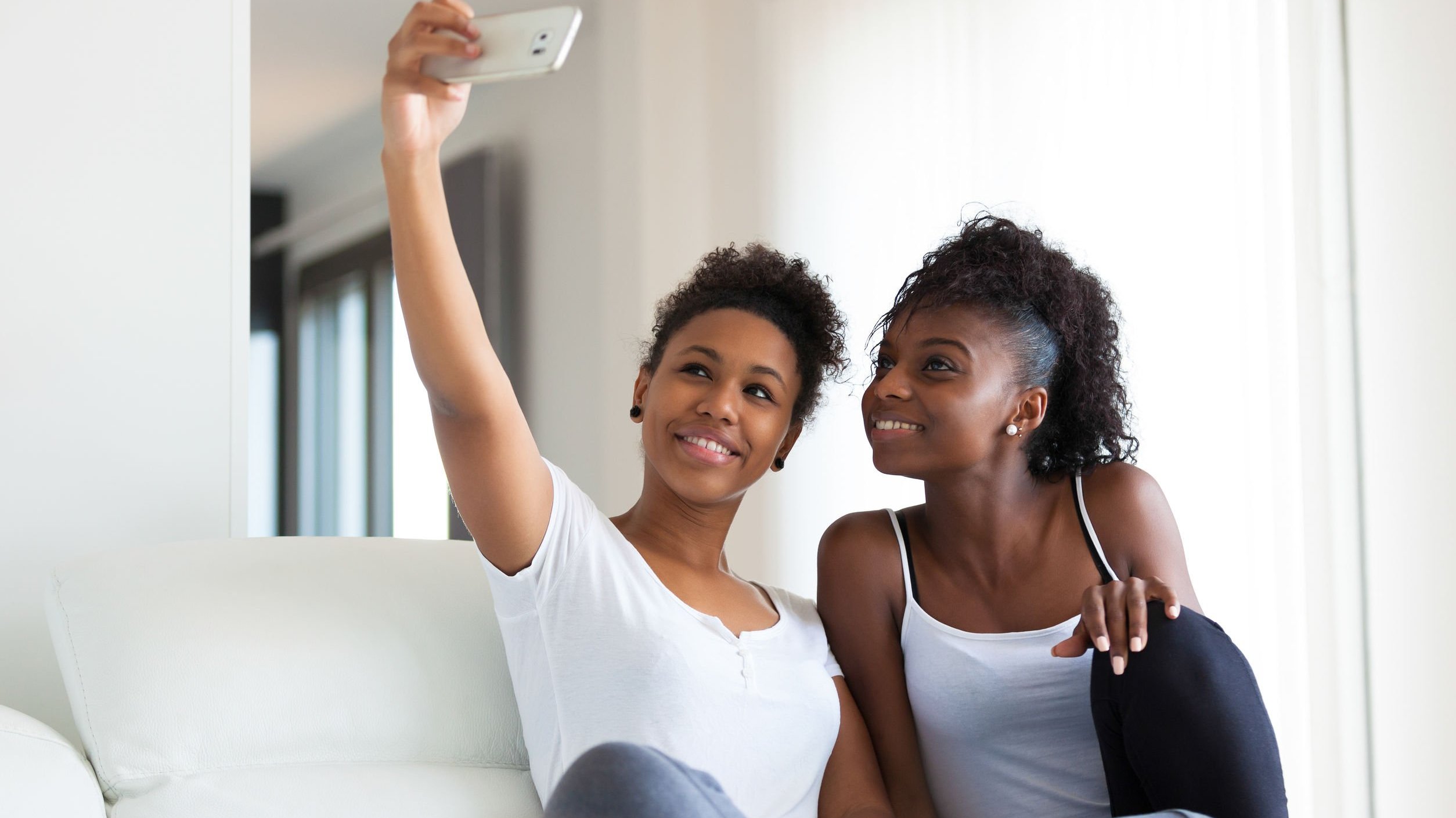 Amigas sentadas no sofá tirando selfie