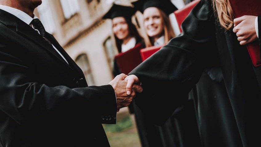 Estudante e docente apertando as mãos