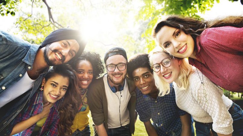 Diversidade de pessoas unidas olhando para foto com árvore ao fundo