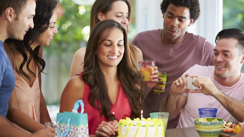 Mulher celebrando aniversário em casa com amigos em volta