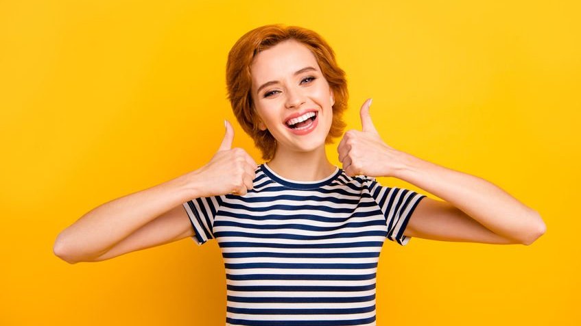 Menina com polegares erguidos e sorrindo