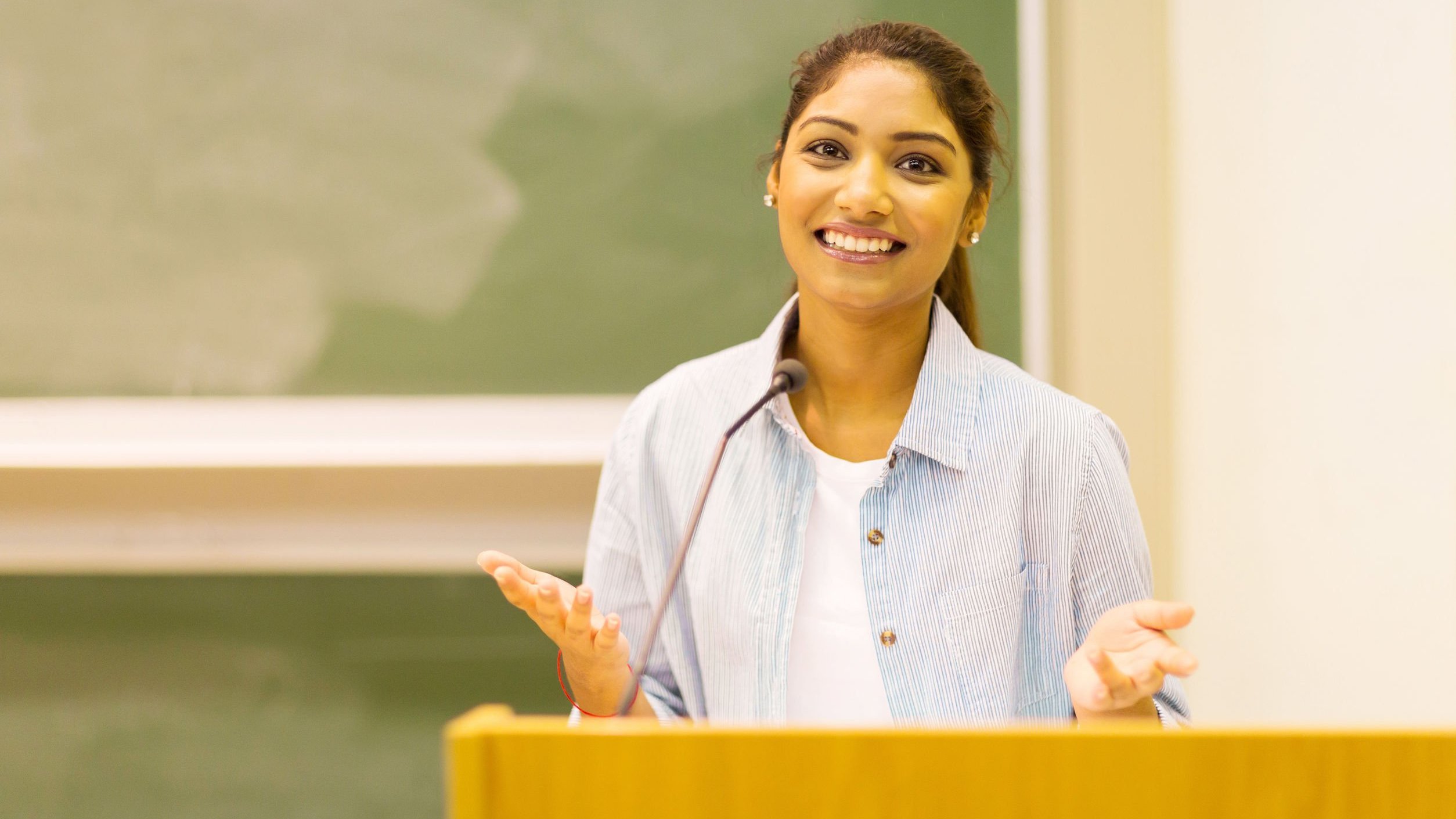 Mulher estudante discursando em sala de aula.