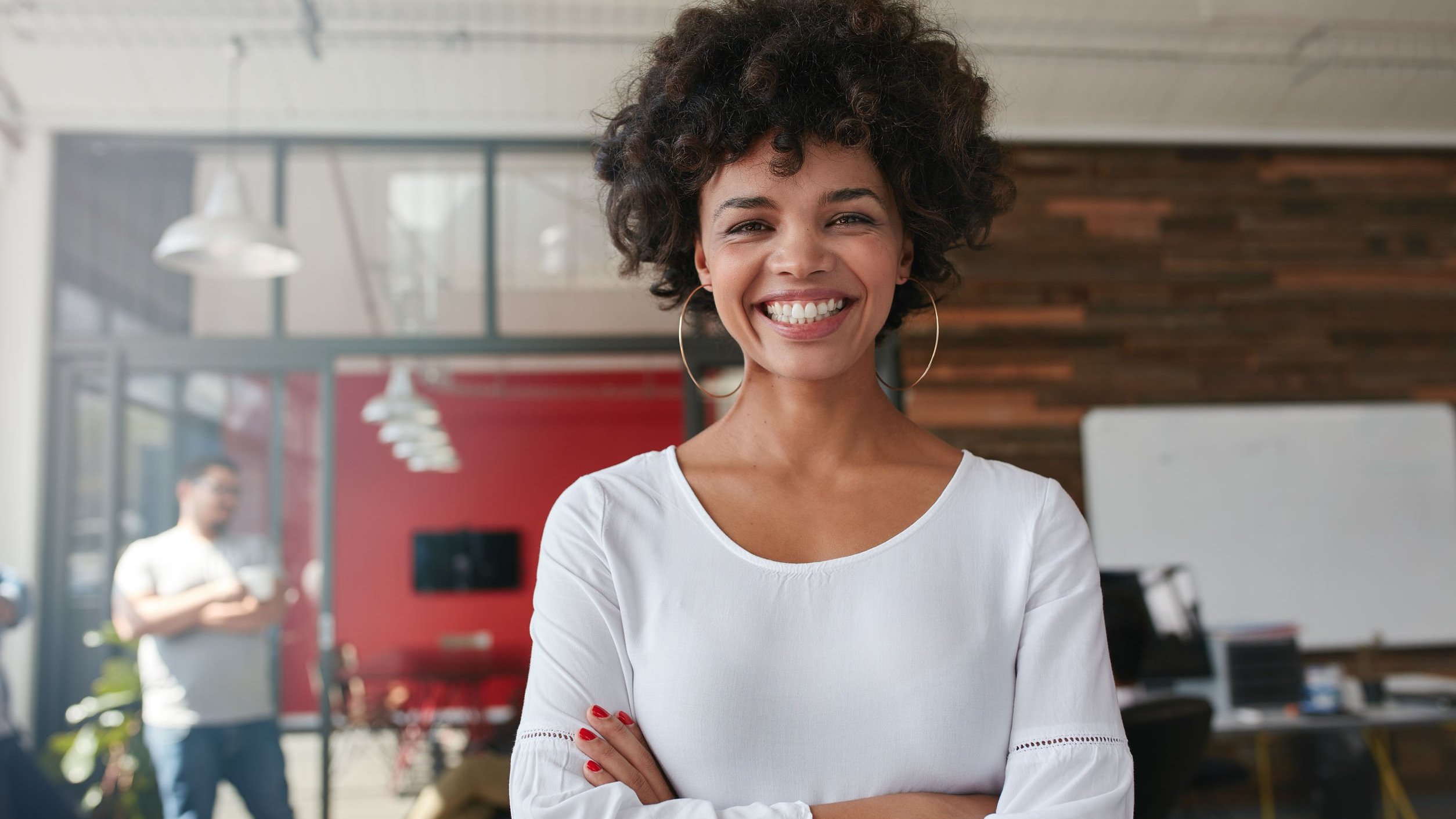 Foto de mulher negra de braços cruzados sorrindo