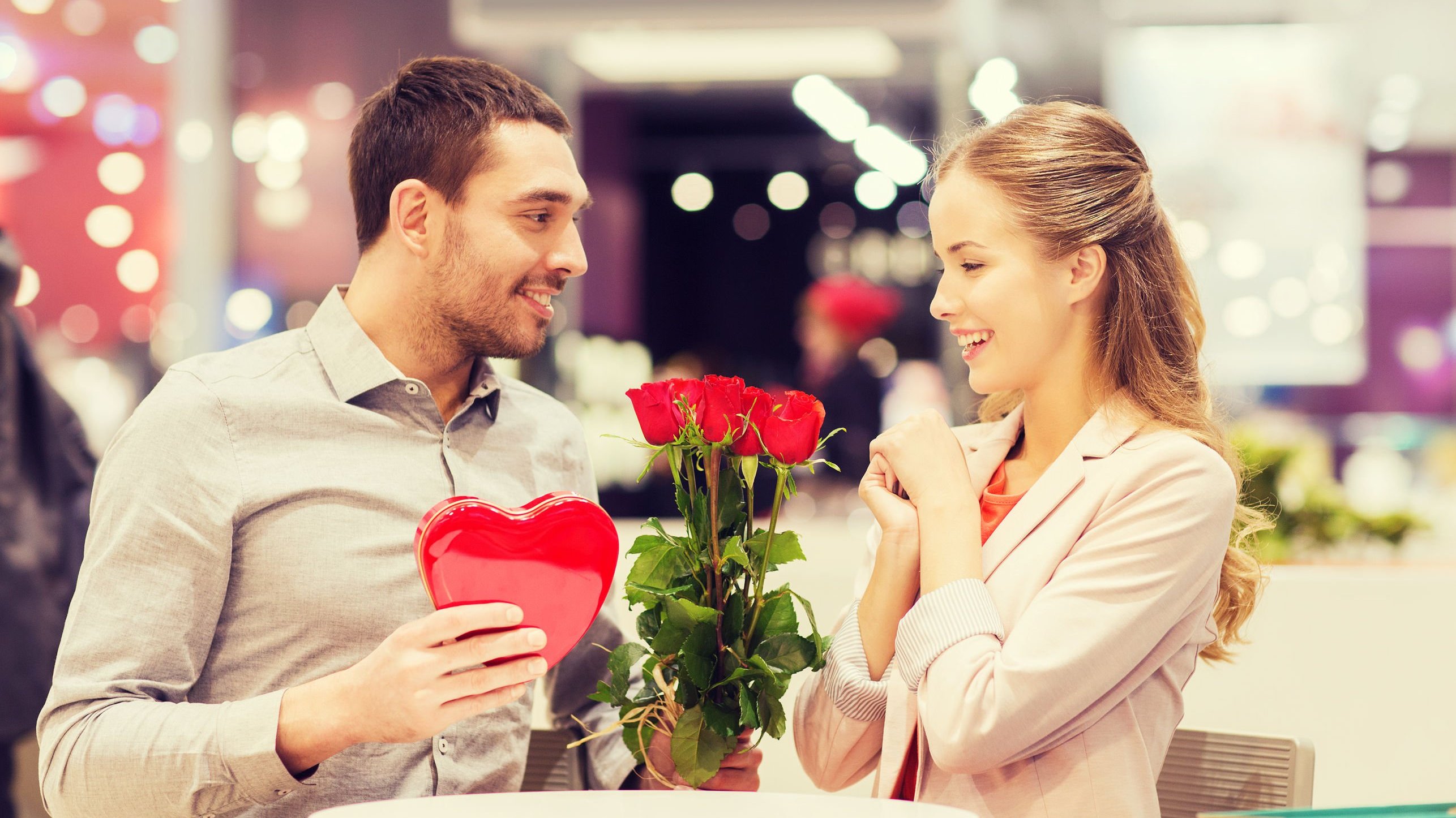 Homem entregando buquê de flores vermelhas para mulher