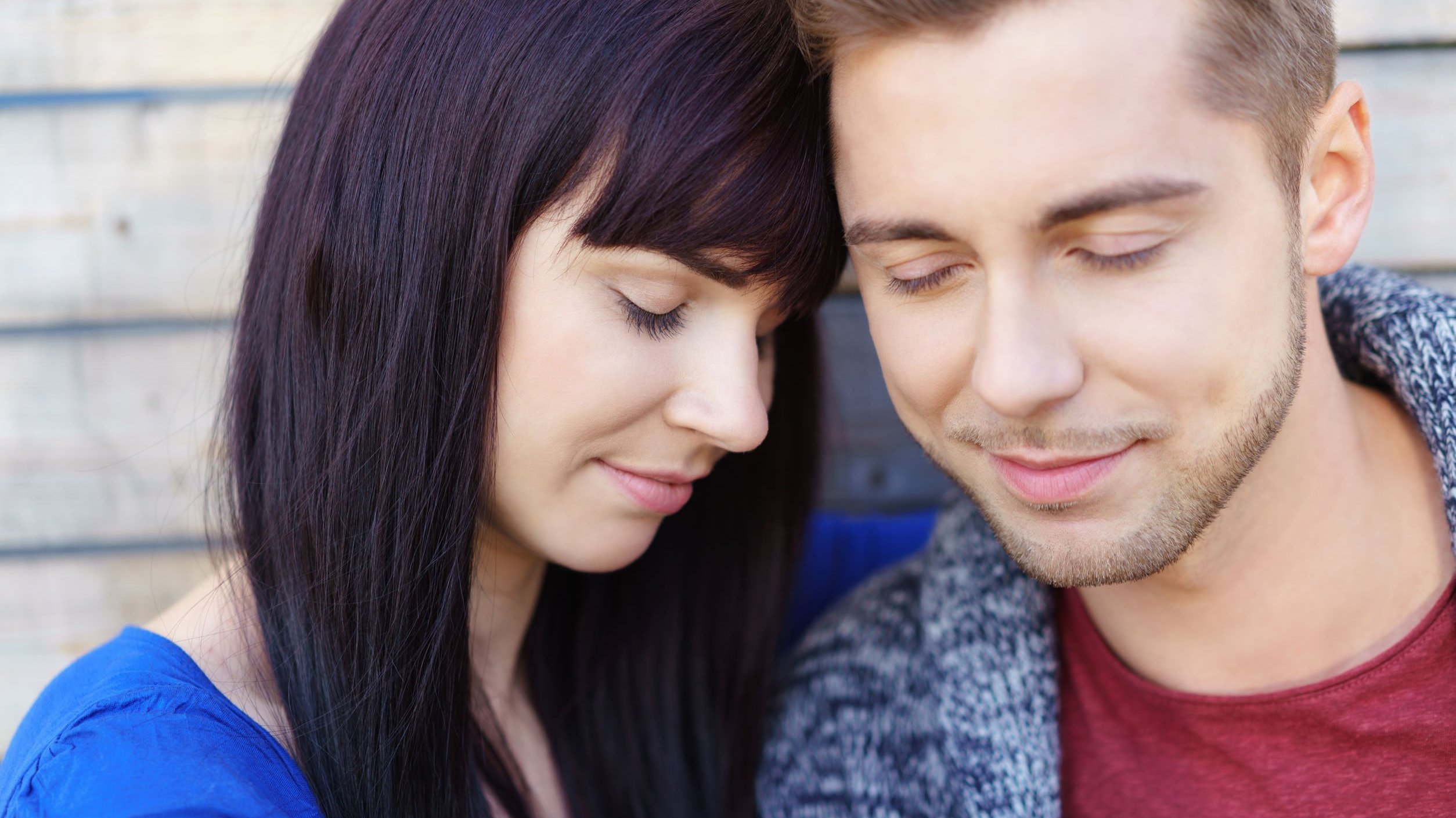 Homem e mulher juntos, de olhos fechados apoiando-se um no outro