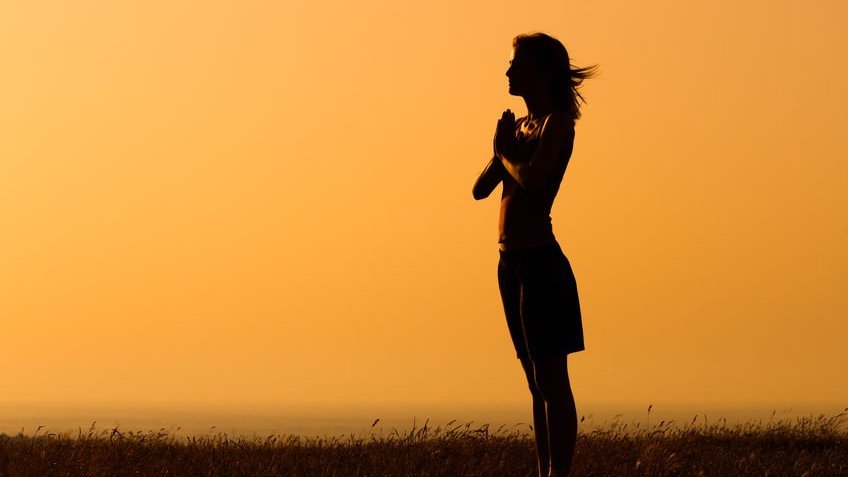 Mulher com mãos unidas em pé em campo