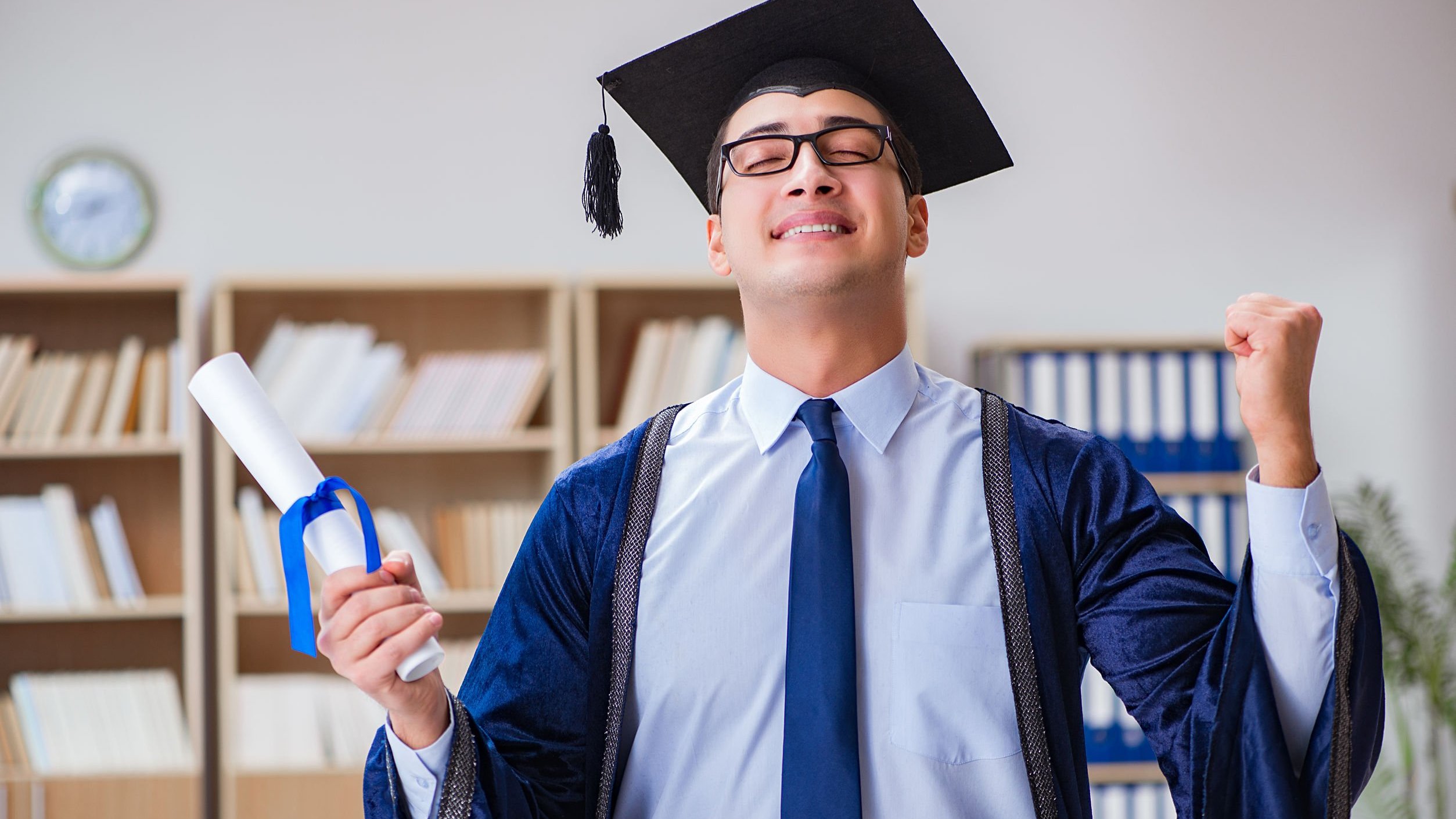 Homem se formando usando capelo e segurando diploma