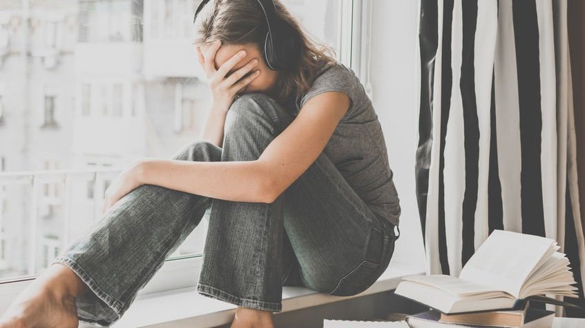 Menina com fone de ouvido e cabisbaixa