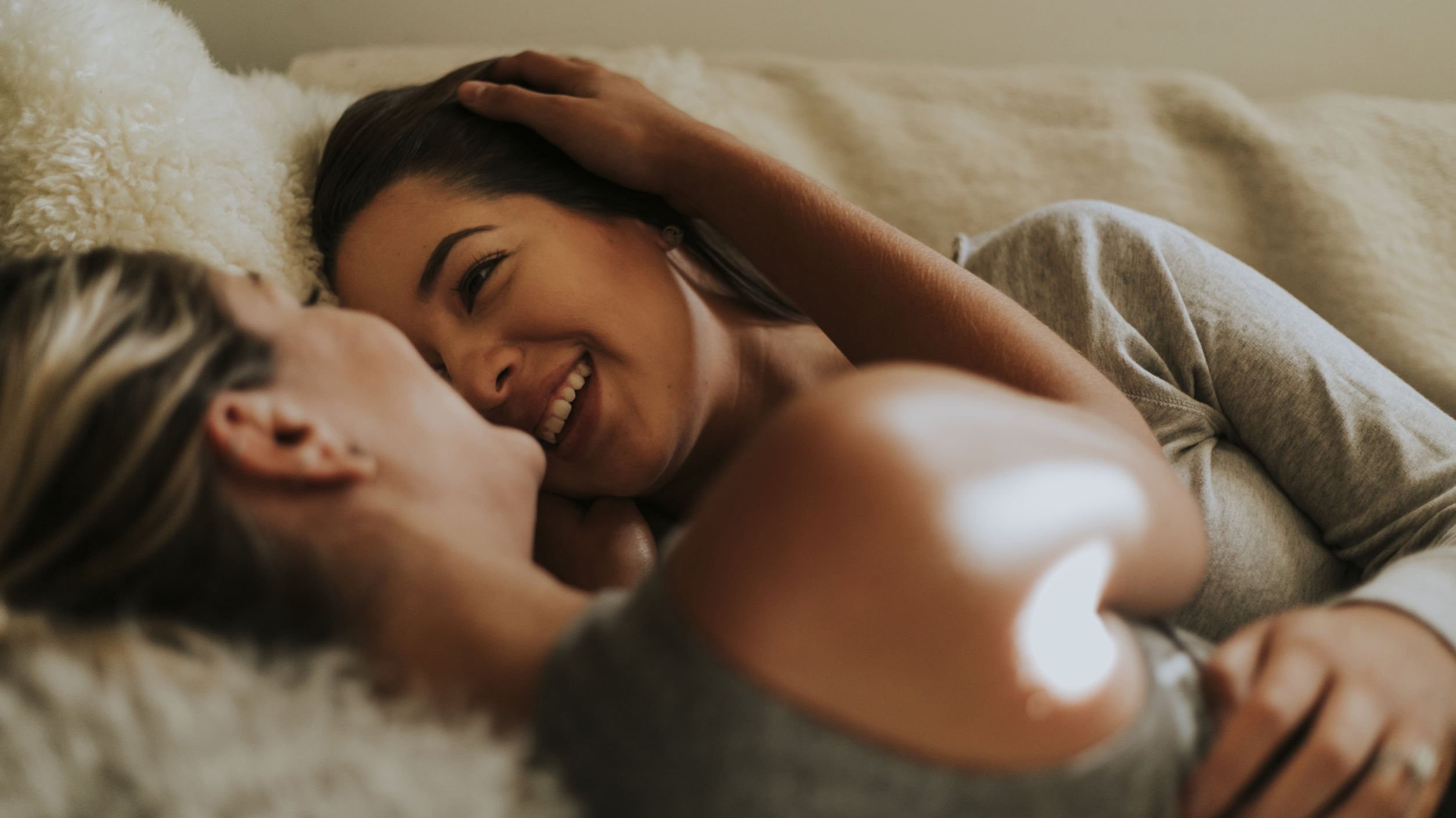 Duas mulheres deitadas na cama sorrindo