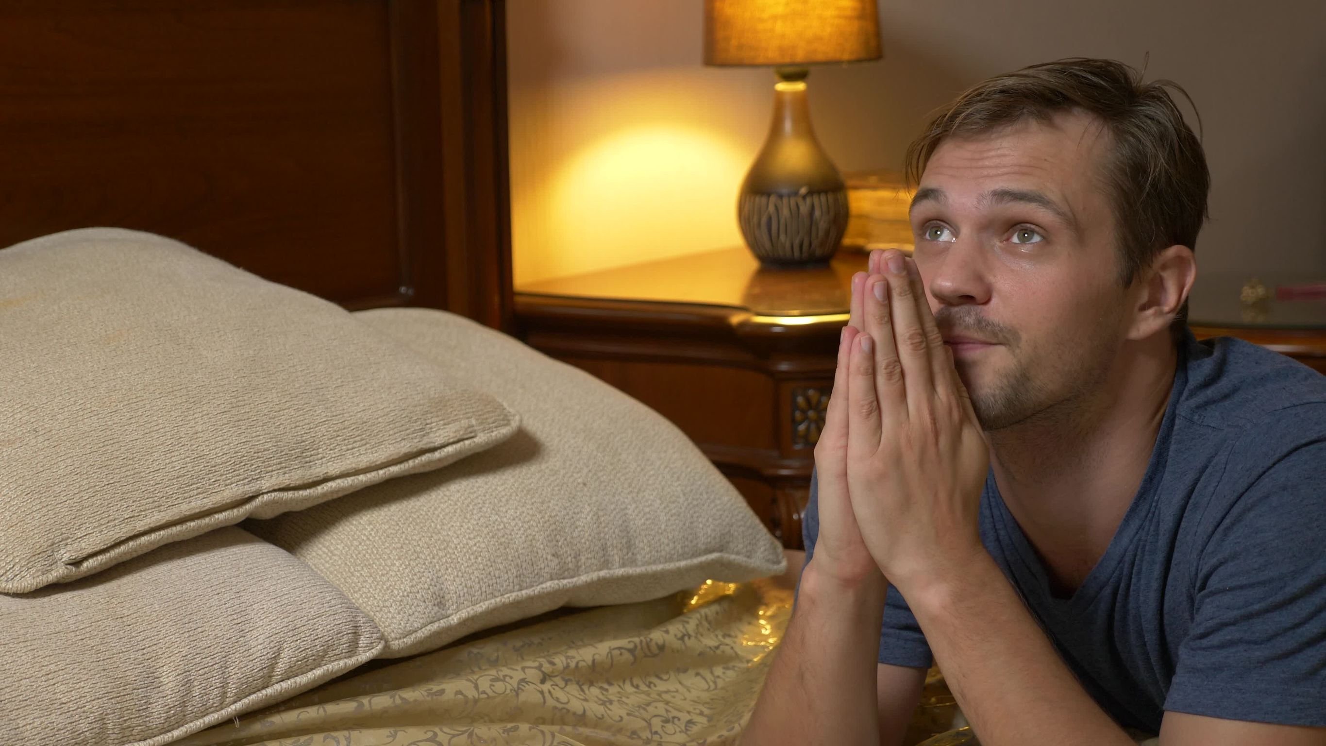Homem orando apoiado em cama