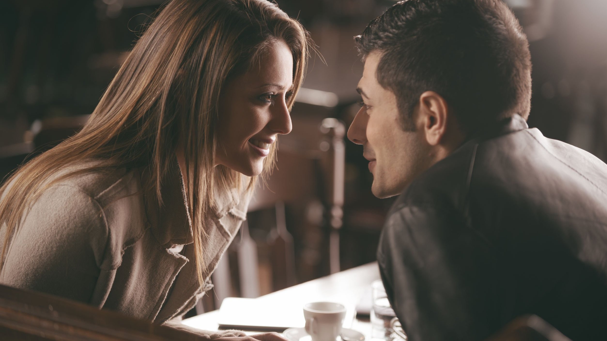 Homem cantando mulher enquanto os dois estão sentados em mesa de restaurante