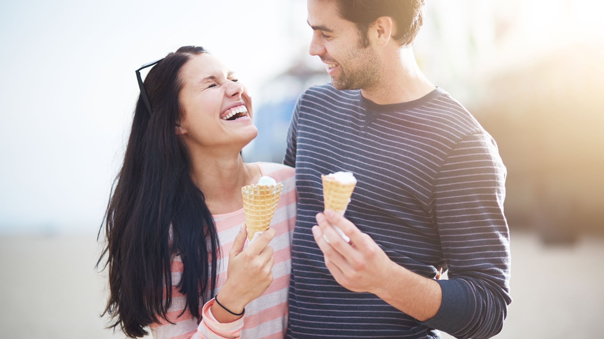 Homem e mulher comendo sorvete e sorrindo