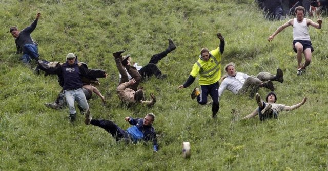 Pessoas correndo atrás de queijo em ladeira