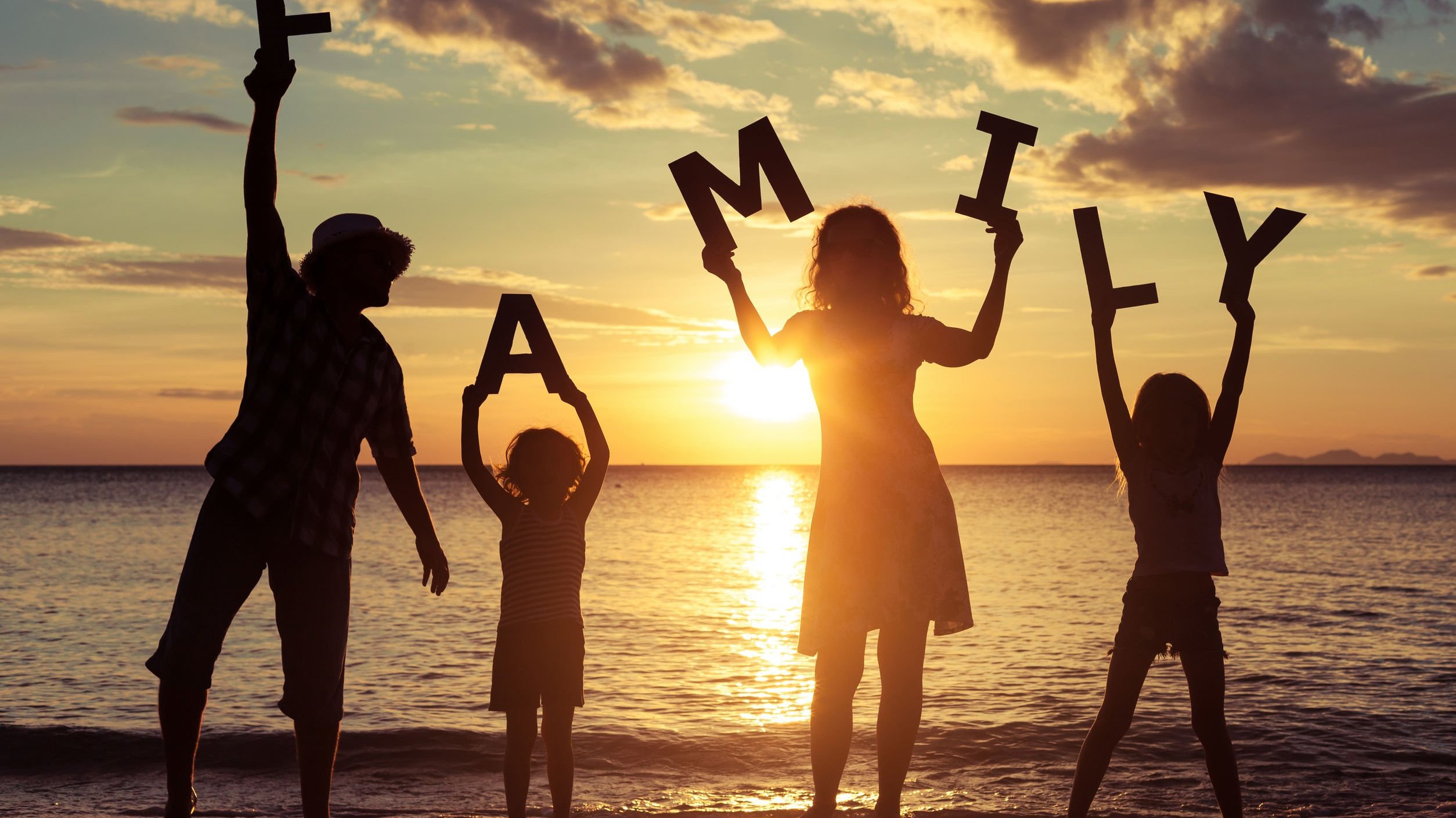 Silhueta de família segurando letras de madeira formando a palavra família em inglês