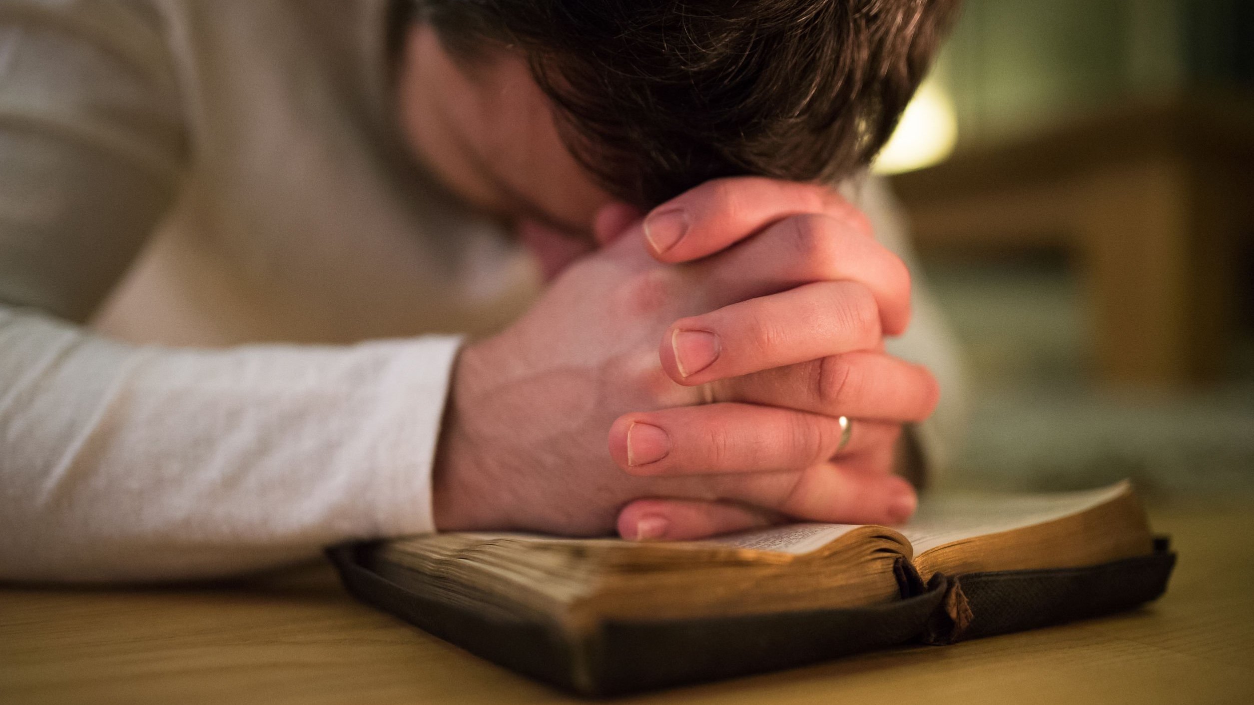 Homem orando apoiando-se em bíblia