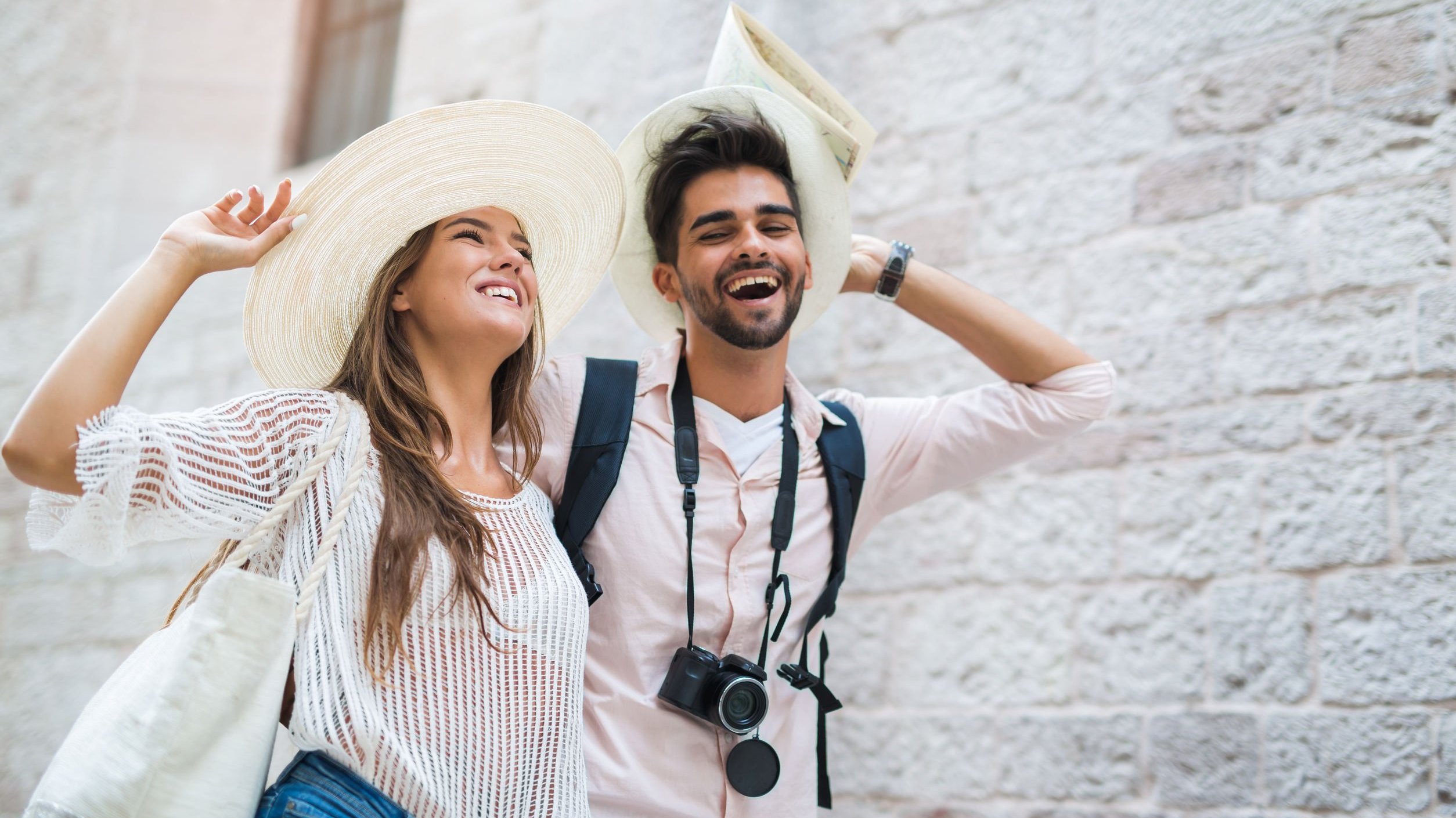 Homem e mulher sorrindo caminhando com os cabelos ao vento