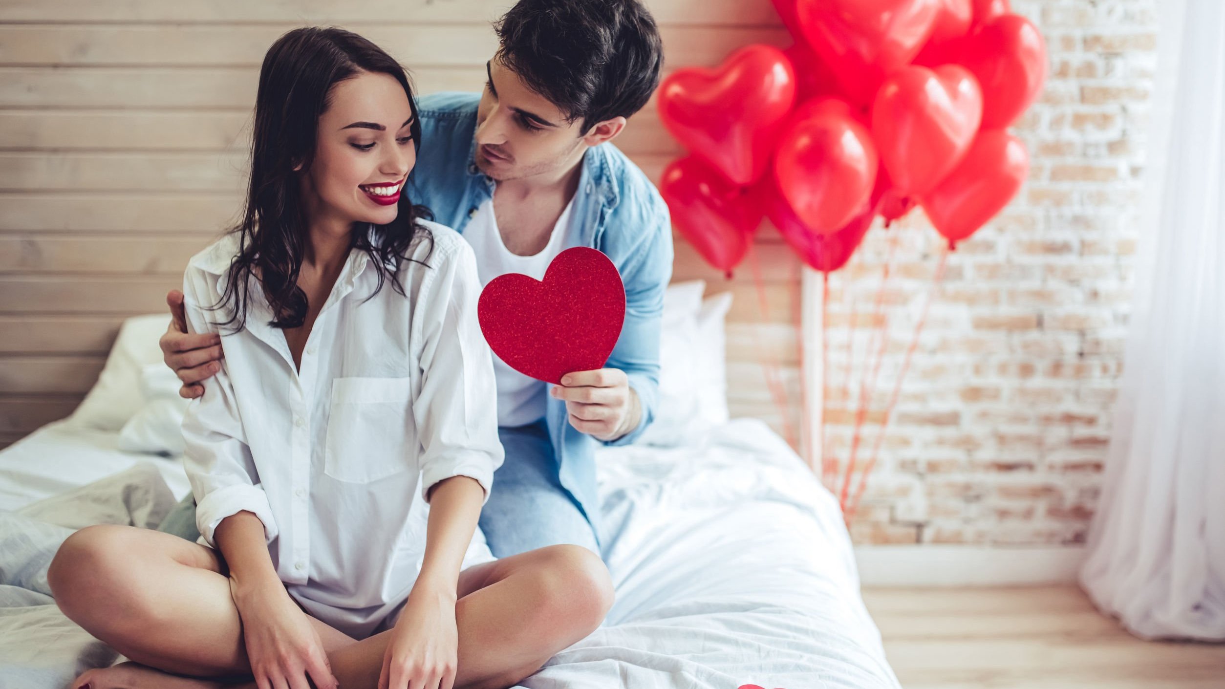 Casal sentado em cama sorrindo