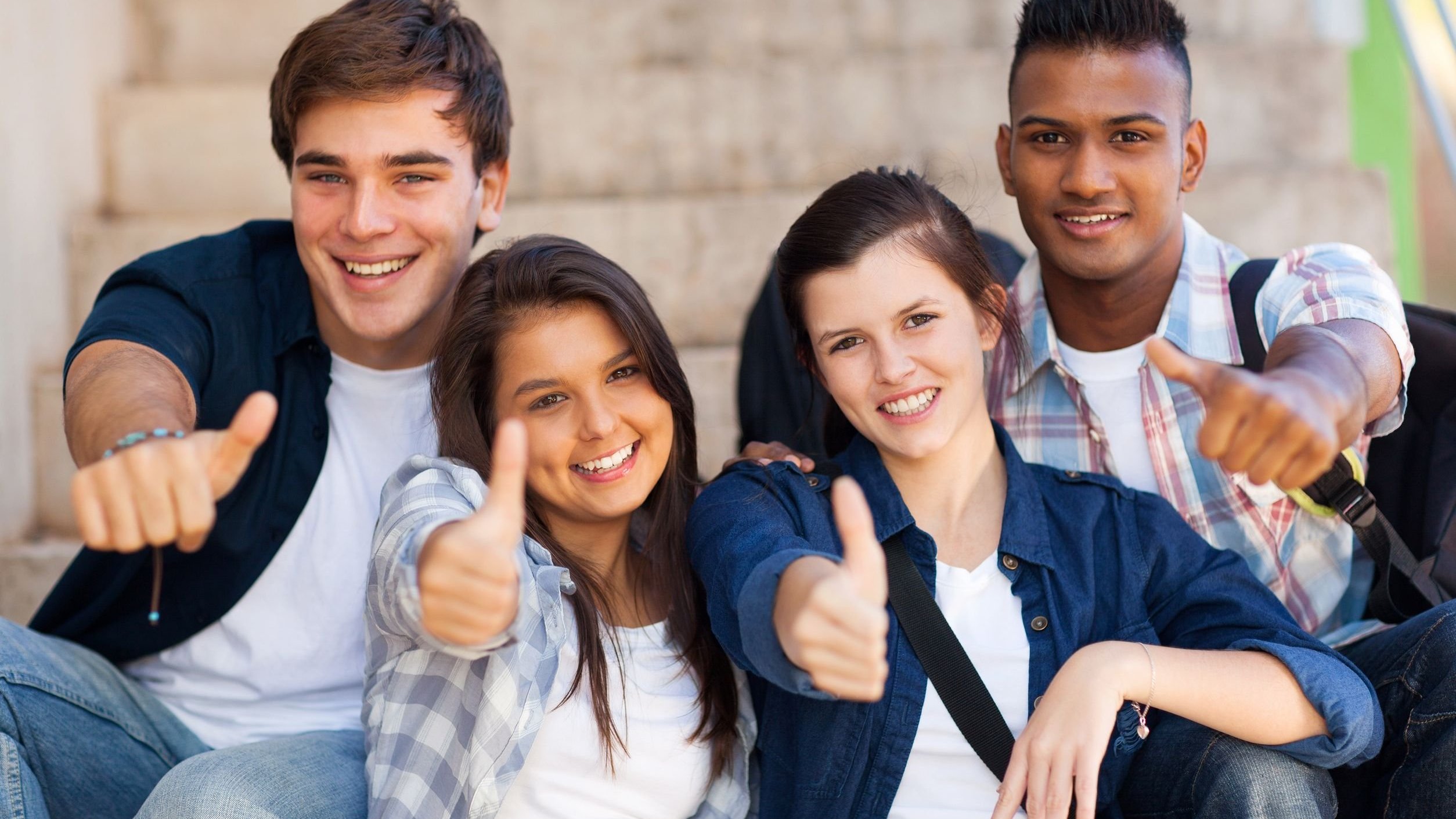 Adolescentes sorrindo e fazendo sinal de jóia com as mãos