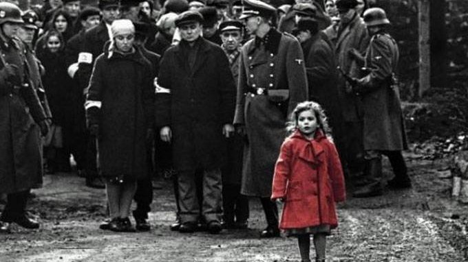 Foto preto e branca de pessoas caminhando, onde somente garotinha está destacada com um casaco vermelho