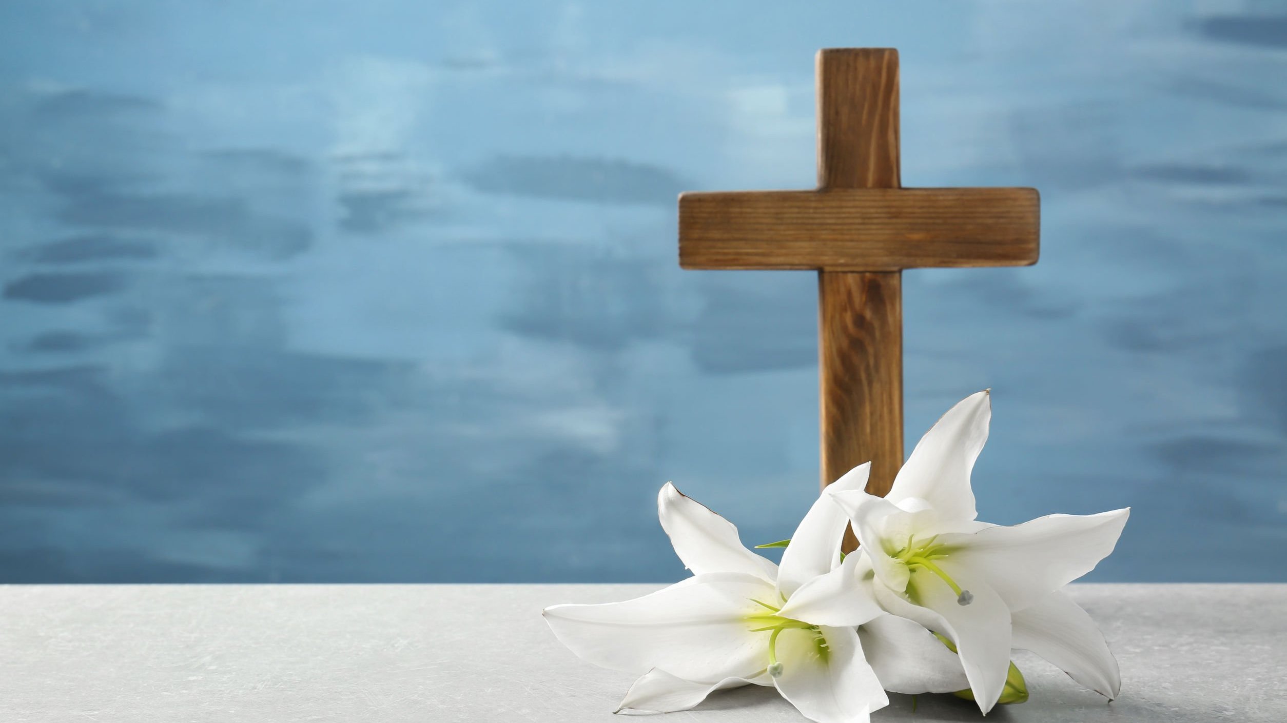 Cruz de madeira em cima de mesa com flores brancas em volta