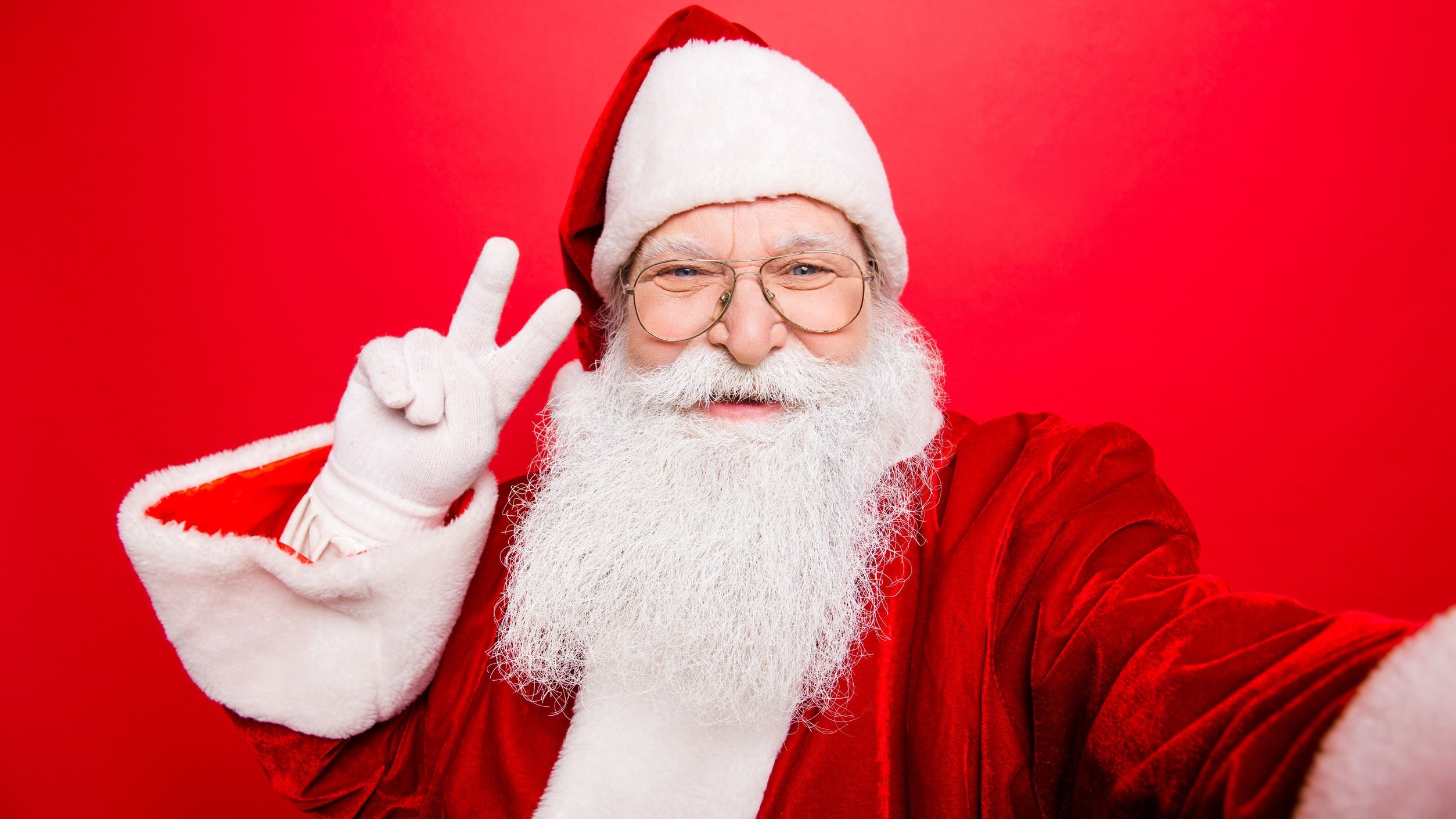 123RF Papai noel fazendo sinal da paz com os dedos, tirando selfie