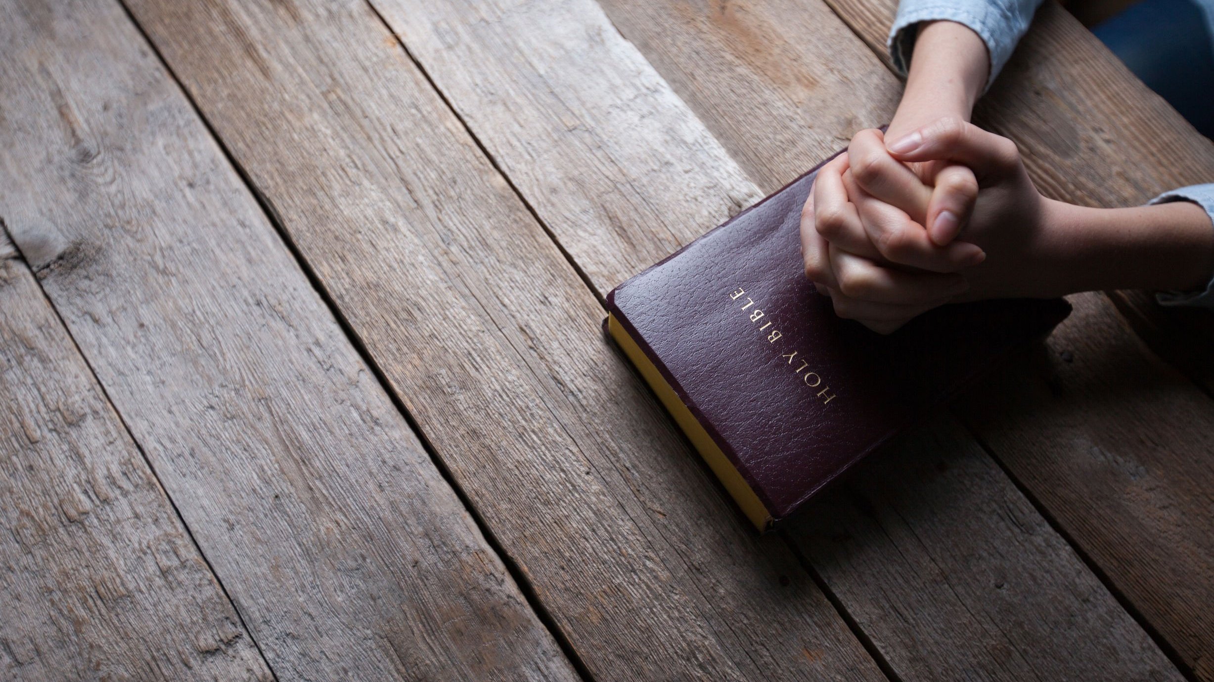 Pessoa orando com as mãos sobre bíblia