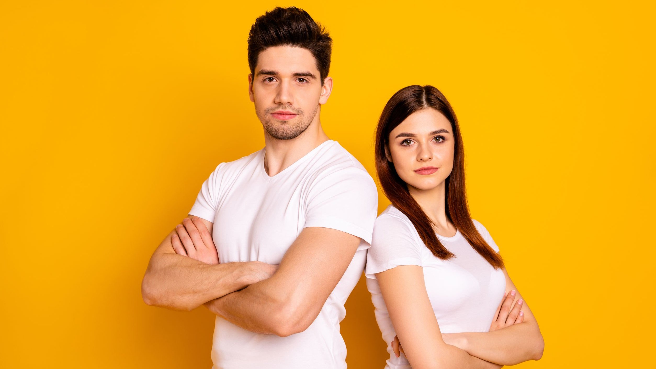 Roman Samborsky/ 123RF Homem e mulher posando de braços cruzados lado a lado, em frente de fundo amarelo