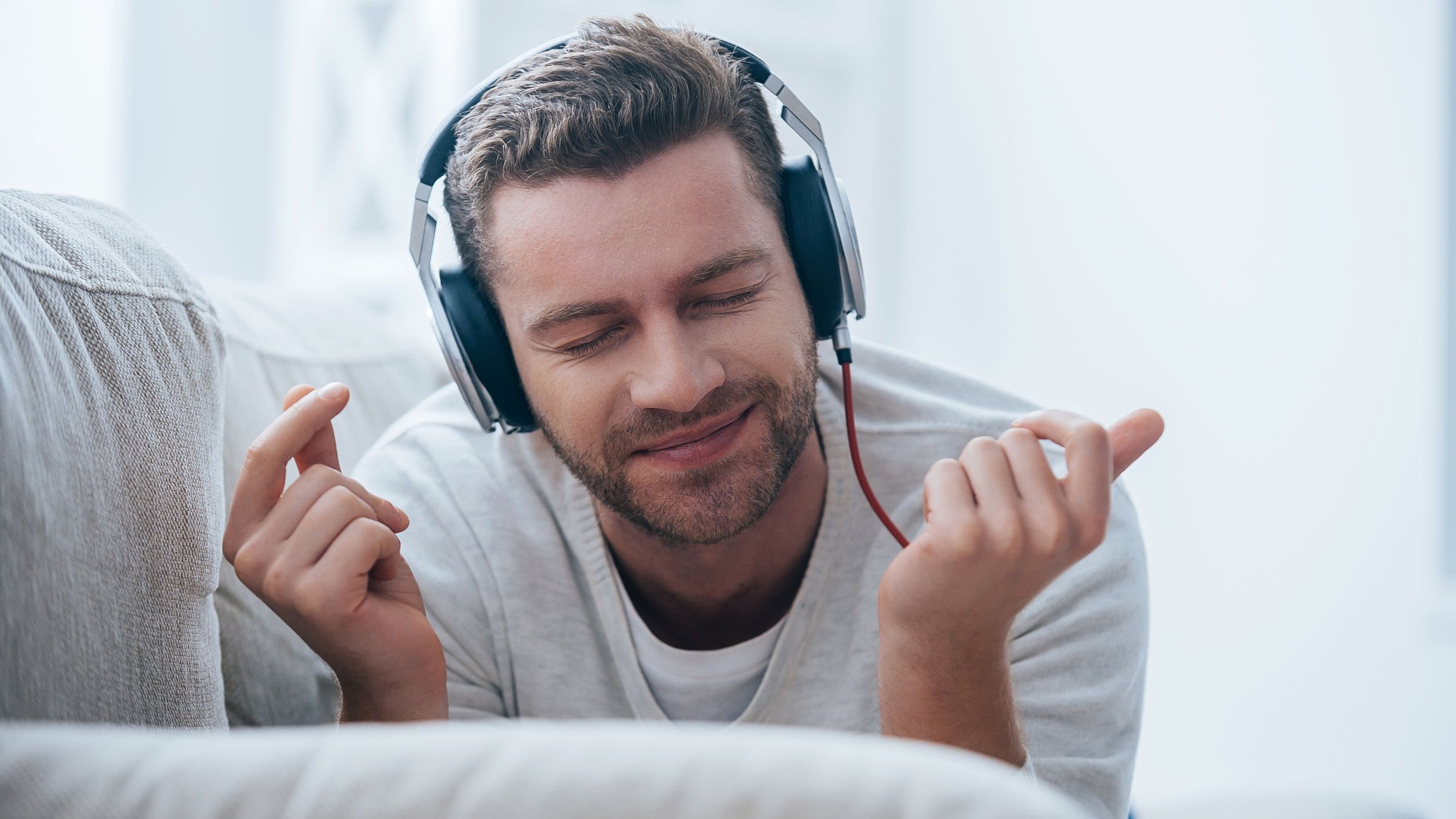 Homem deitado, com fones de ouvido, escutando música