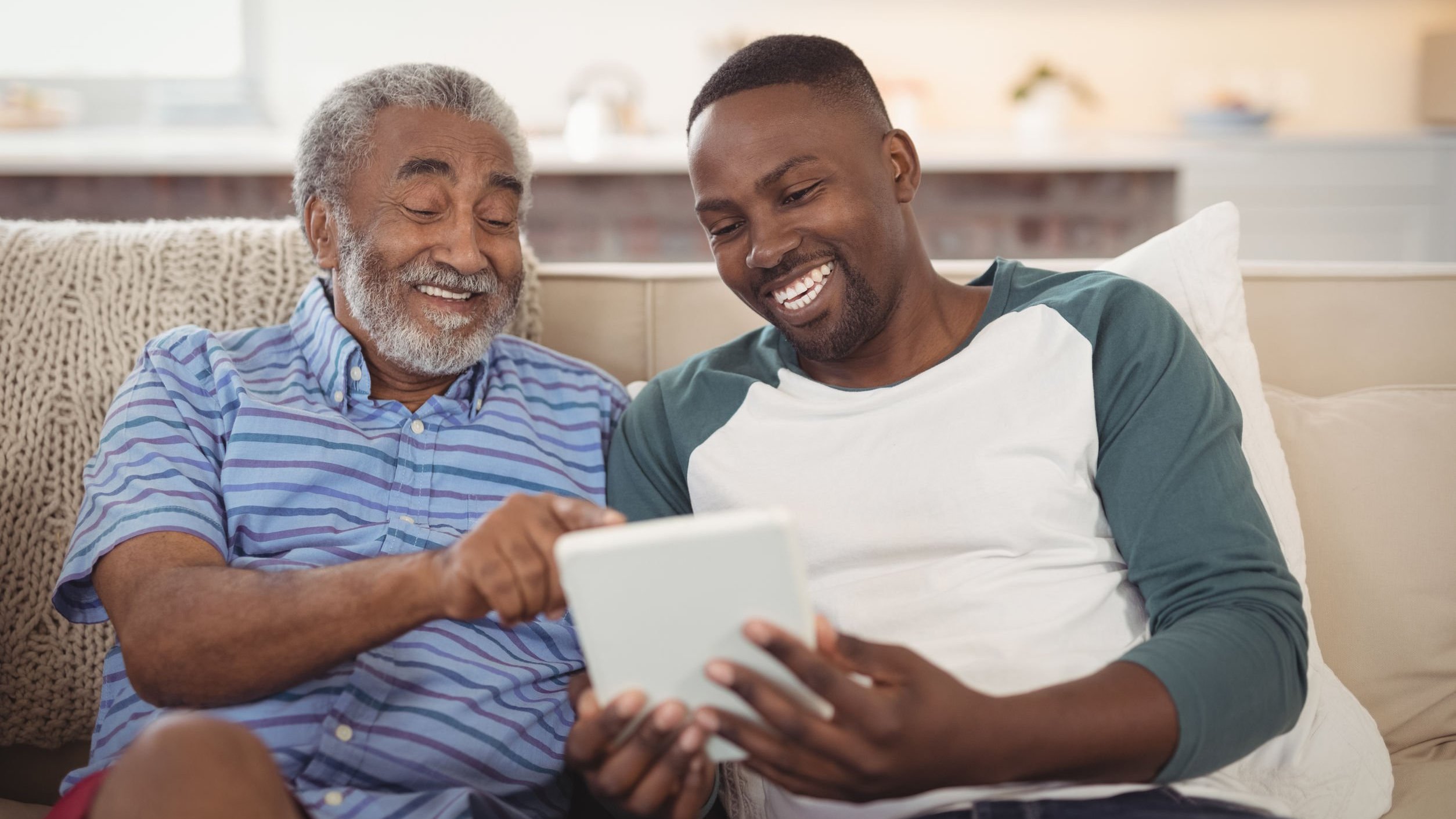 Foto por 123RF Homem jovem ao lado de um senhor segurando um tablet.