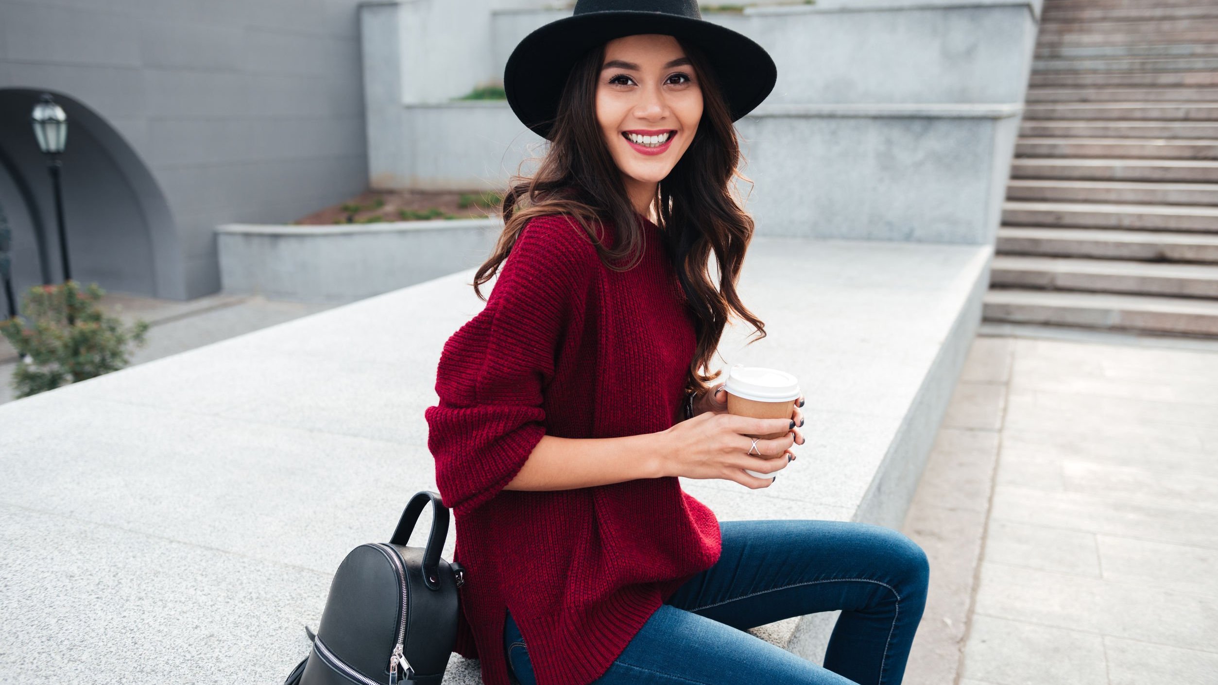 Dean Drobot / 123RF Mulher sentada sorrindo segurando café