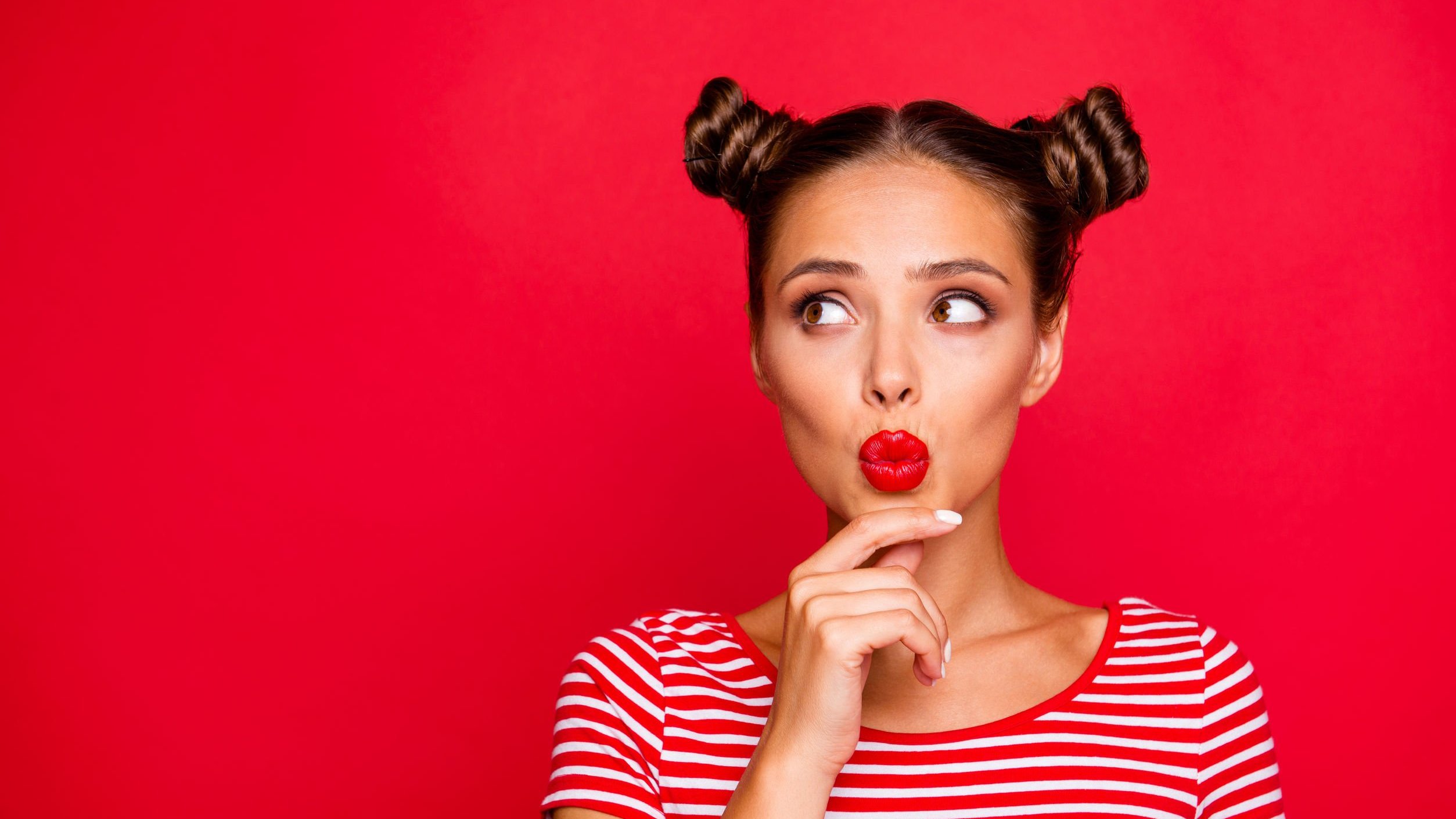 Mulher com expressão de dúvida, parada em frente de fundo vermelho