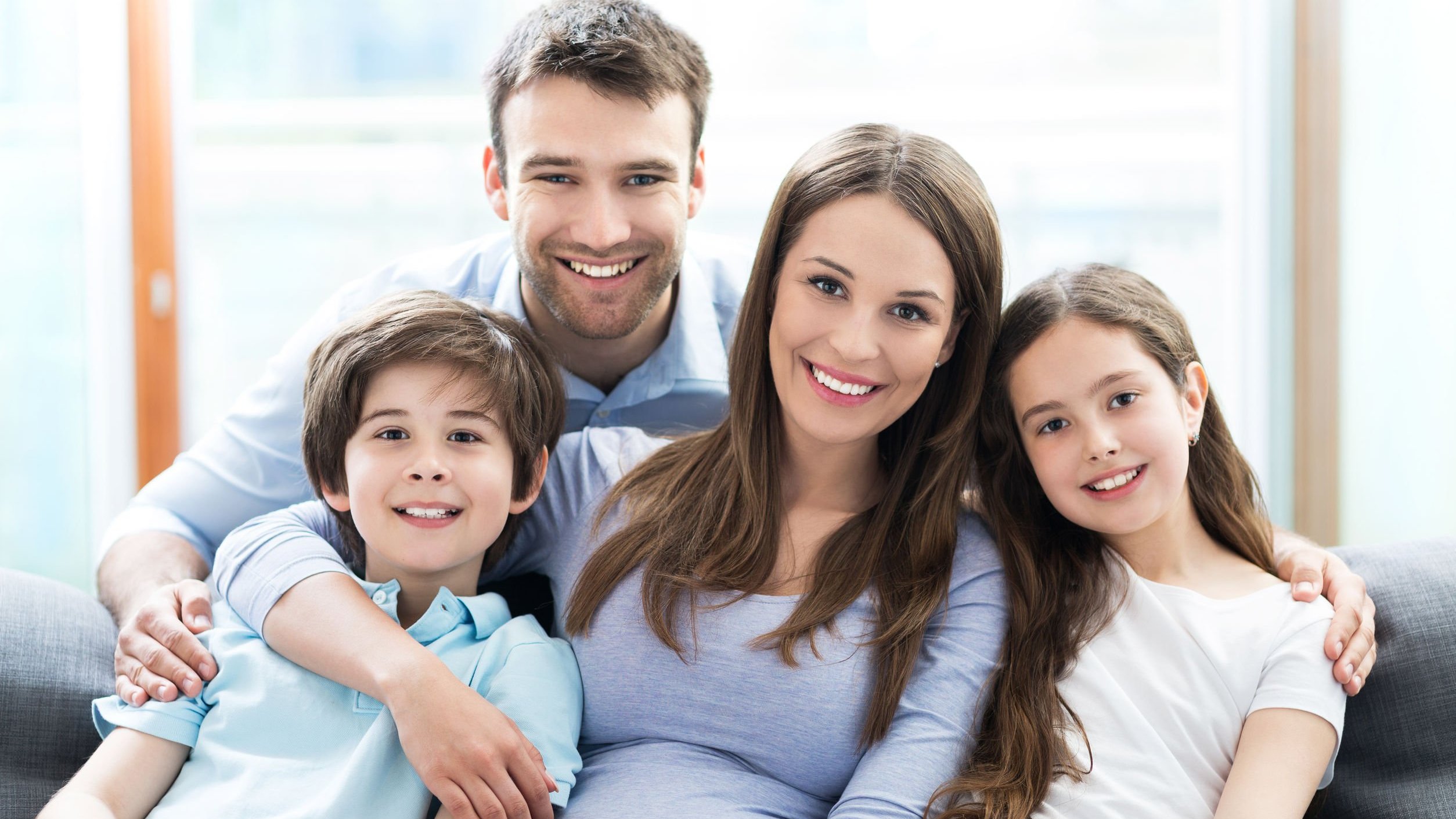 Família posando para foto sentados em sofá, sorrindo