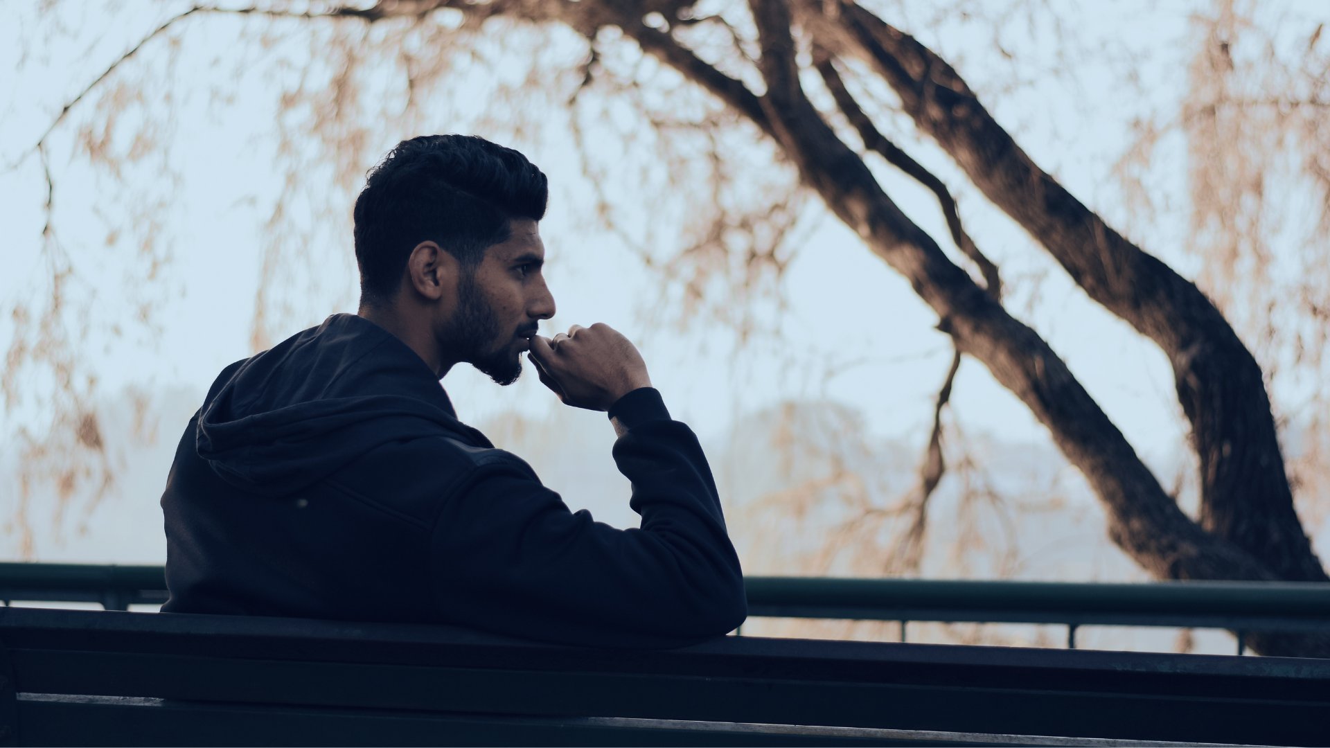 Chinmay Singh / Canva Homem pensativo sentado em um banco de praça