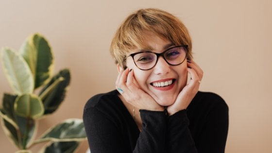 Mulher sorrindo apoiando suas mãos no rosto