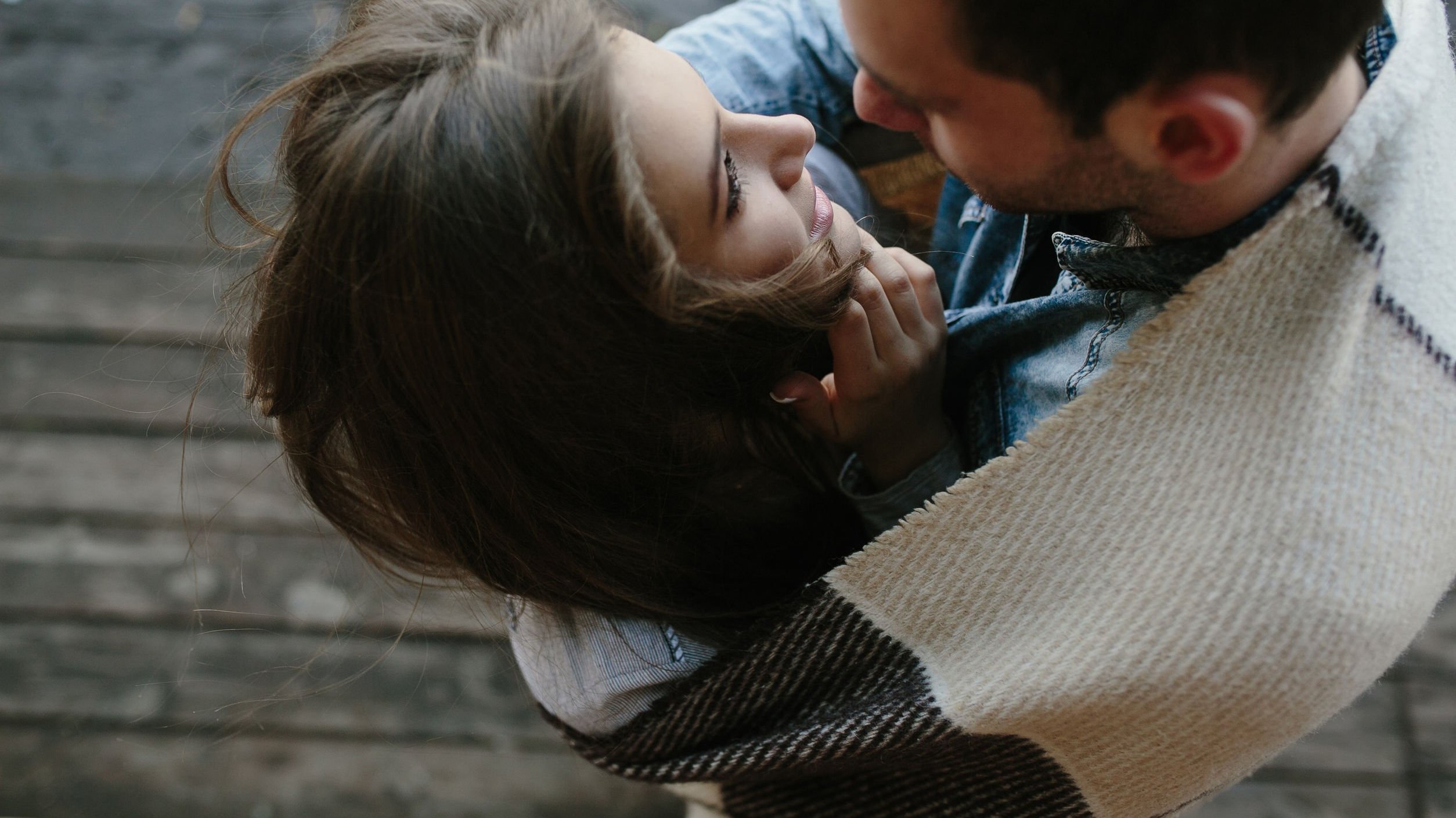 Homem abraçando mulher, ambos enrolados em um cobertor