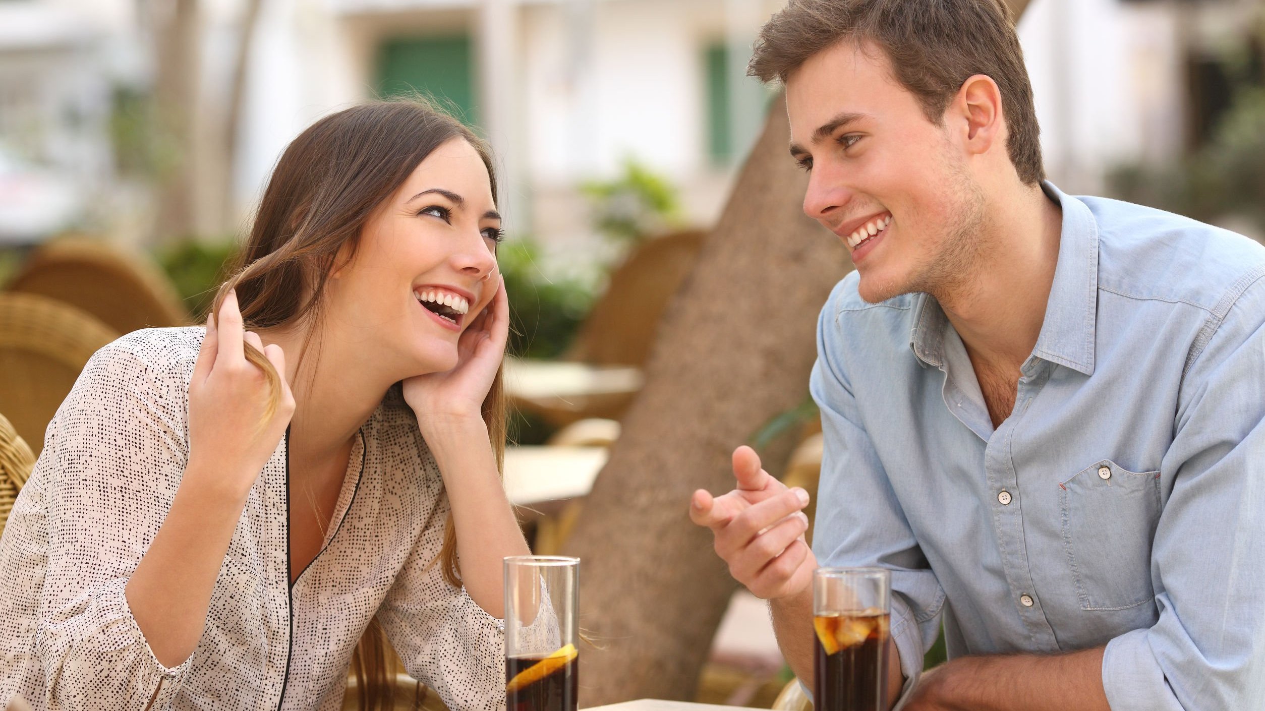Homem e mulher conversando e sorrindo em mesa de restaurante