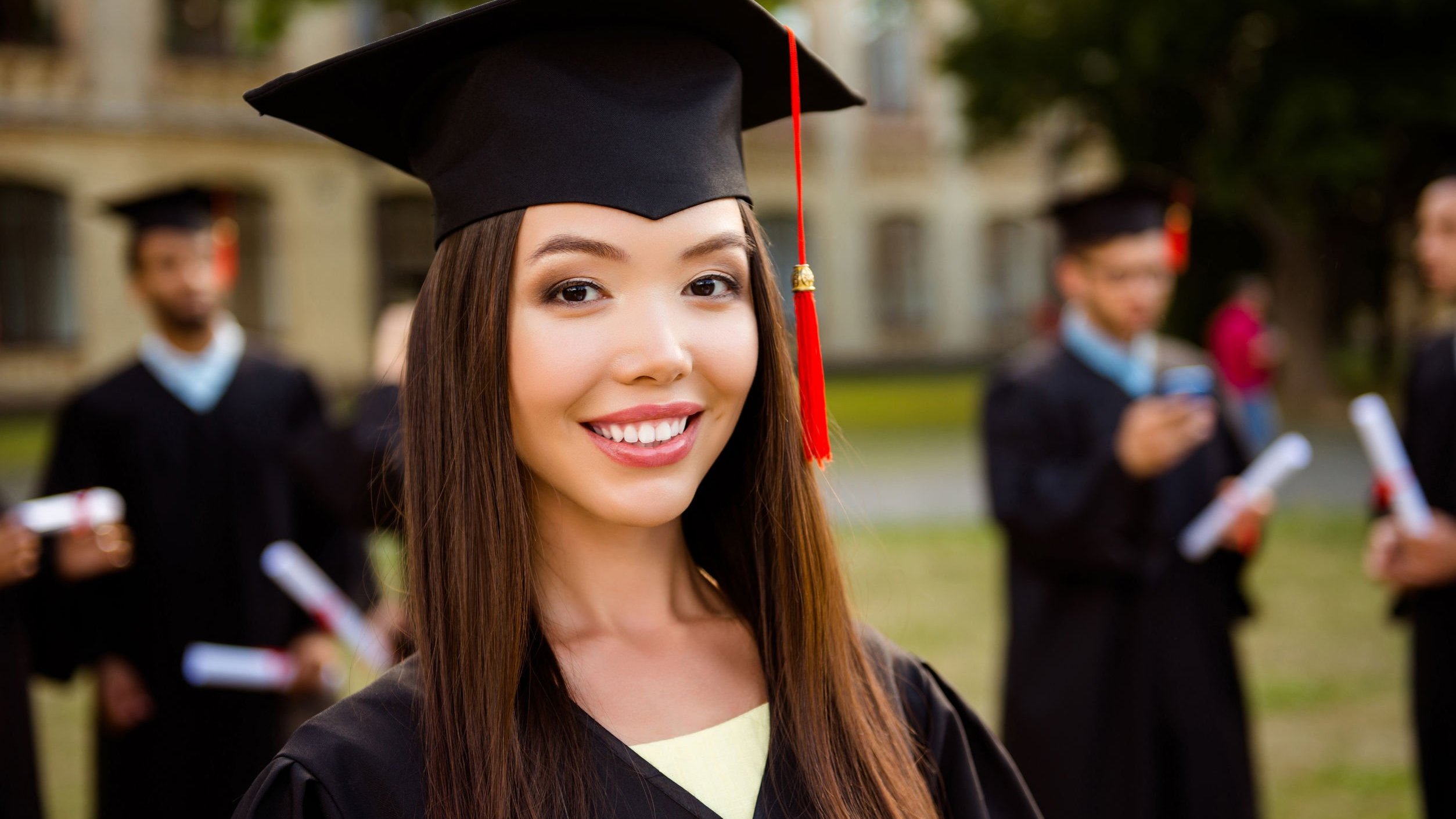 Mulher sorrindo, usando capelo de formatura