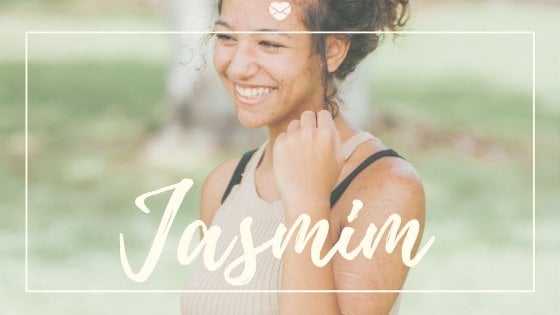 Nome Jasmim escrito em branco sobre foto de mulher jovem, com acne na pele, dando risada em parque.