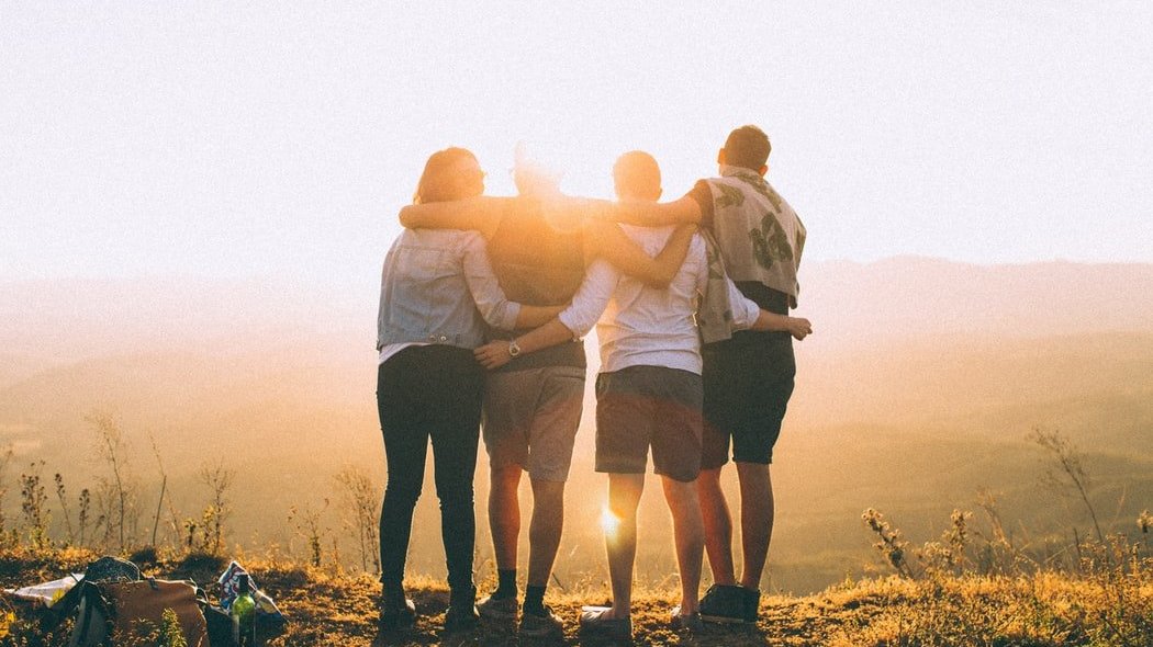 Amigos abraçados olhando por do sol