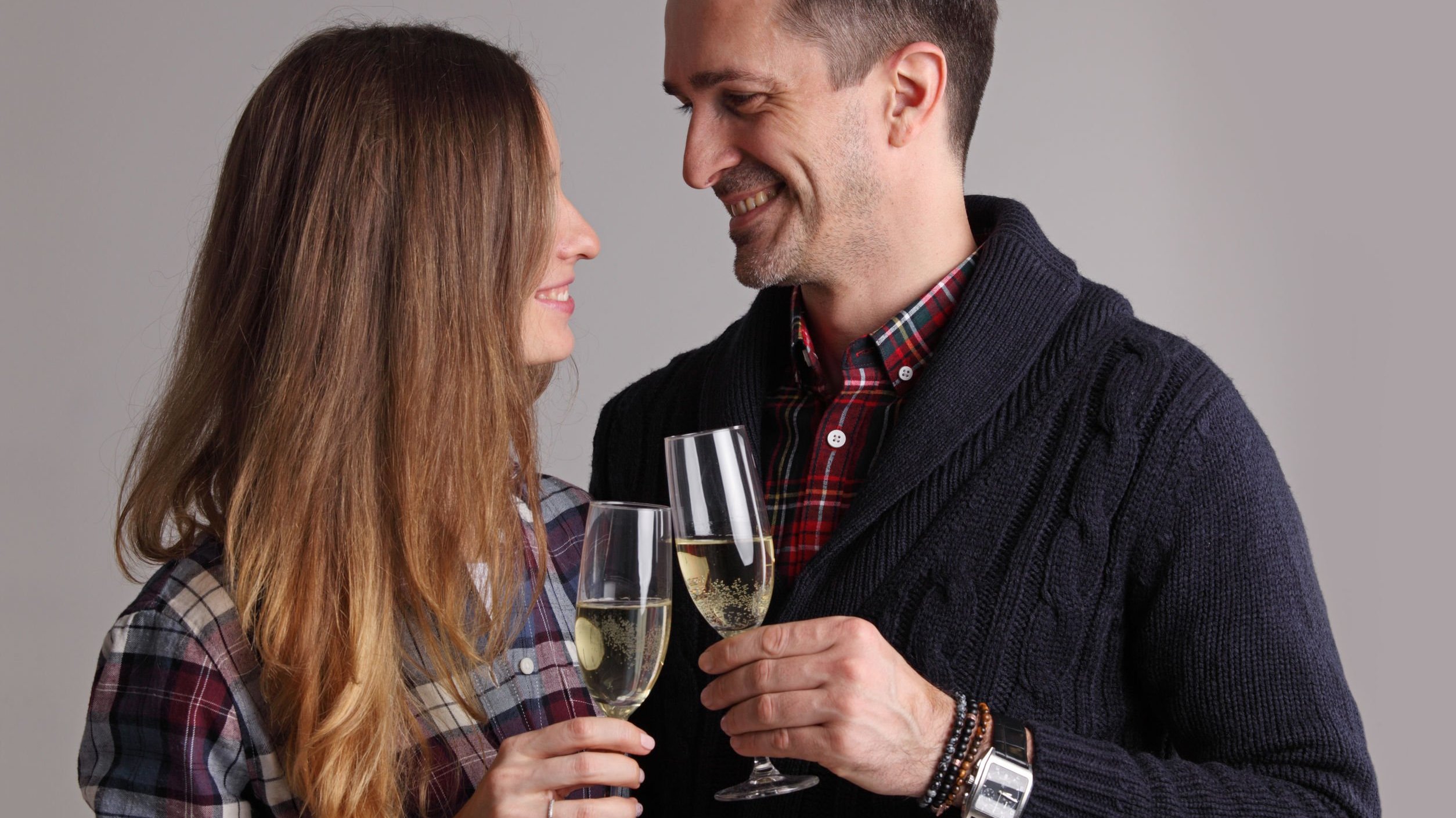 Homem e mulher sorrindo, brindando com taças de champanhe