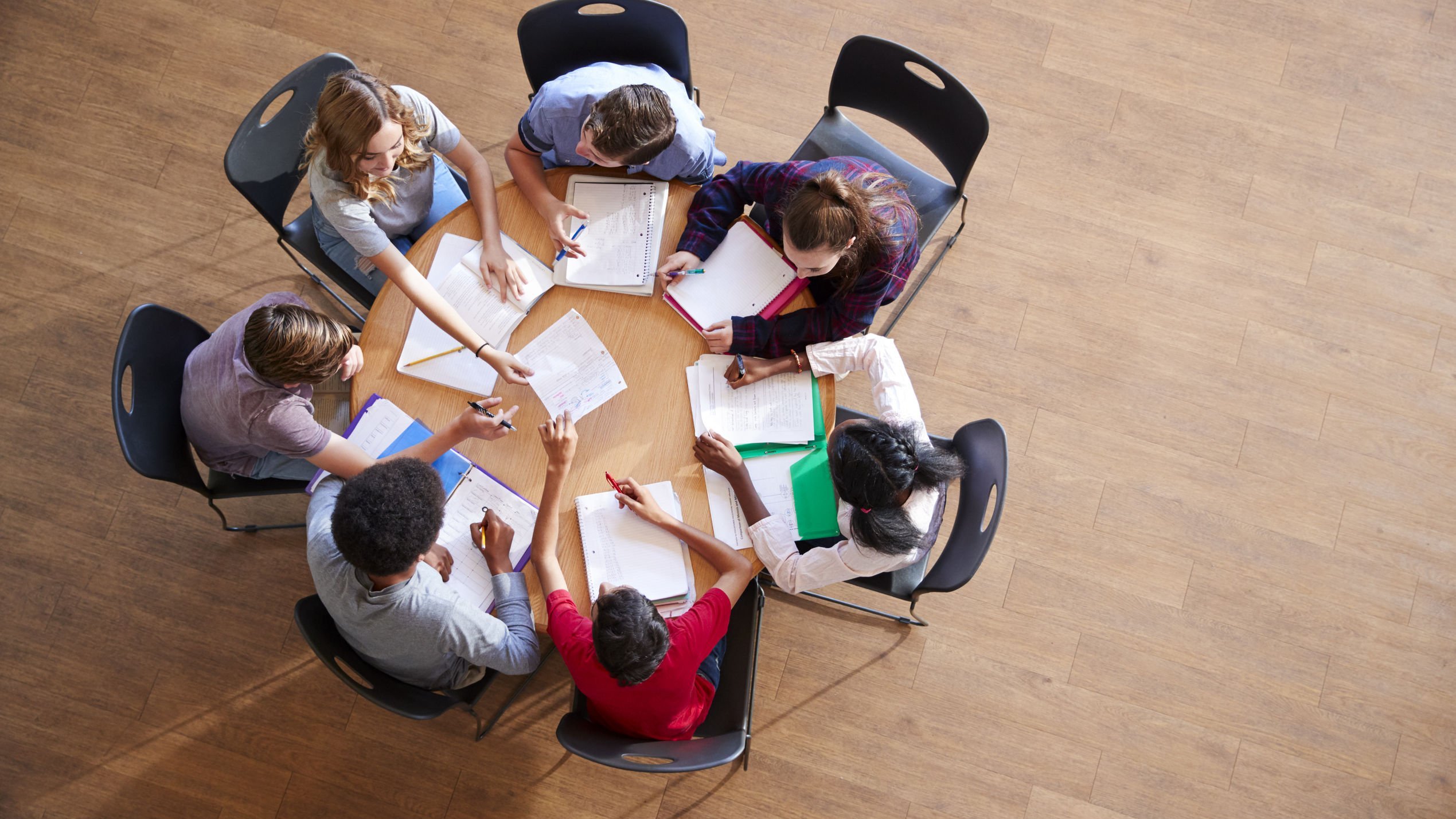 Grupo de estudantes reunidos sentados fazendo trabalho