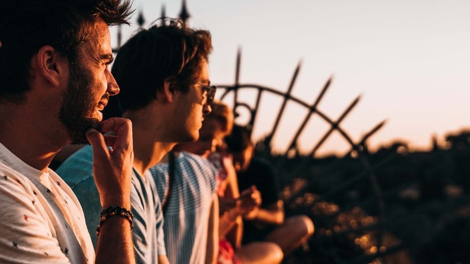 Amigos sentados em laje de casa observando por do sol