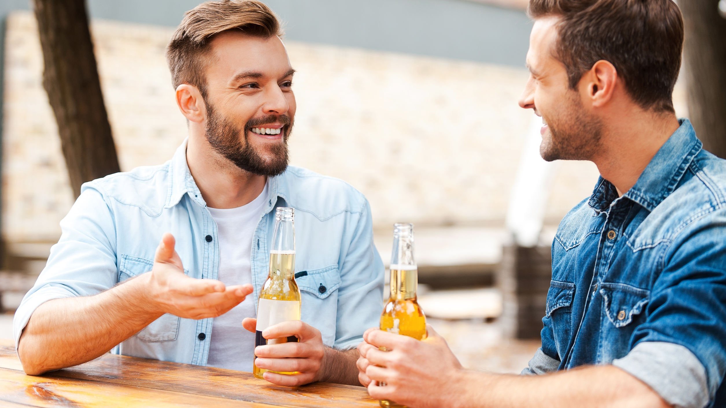 Homens conversando bebendo cerveja sentados em mesa de restaurante