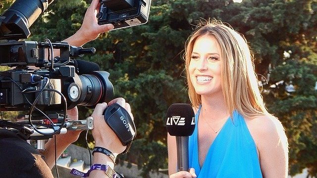 Neva79 / Pixabay Mulher sorrindo e segurando microfone em frente a câmeras