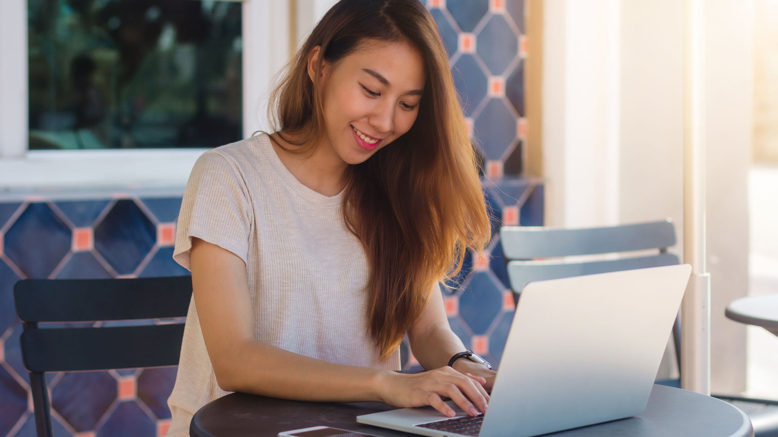 Mulher sorrindo e digitando em notebook