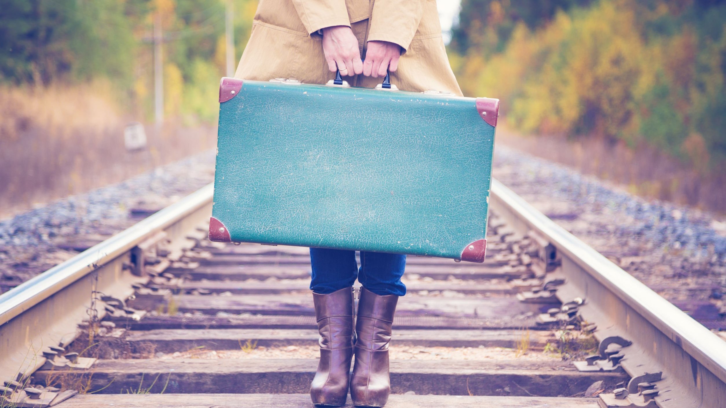 Mulher segurando mala de viajem em trilho de trem