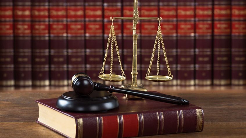 Andriypopov /123RF Um martelo e um livro jurídico com a escala de justiça na mesa do tribunal