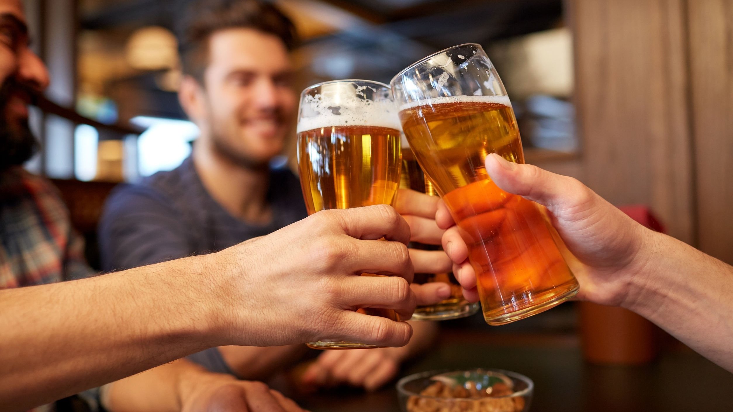 Pessoas brindando com cerveja em happy hour.