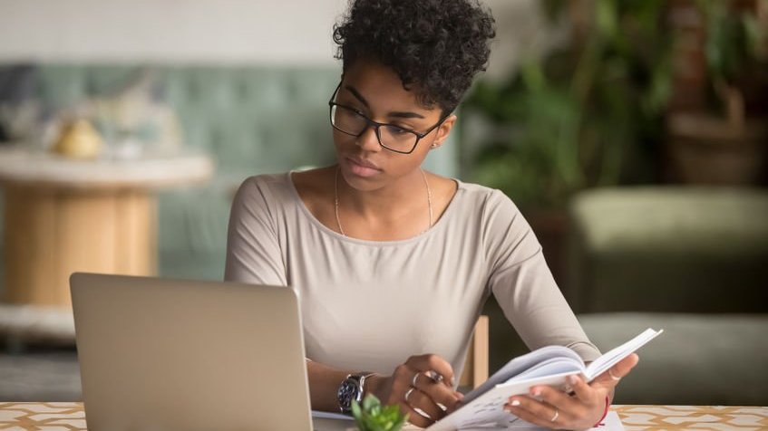 Mulher na mesa de casa com notebook estudando